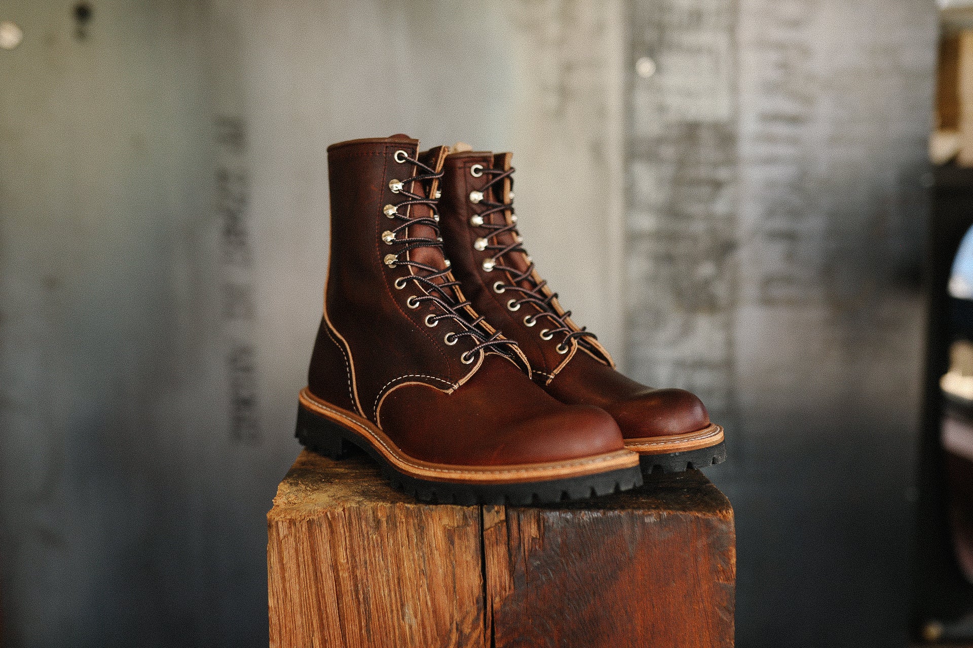 Pair of brown leather work boots with black laces displayed on rustic wooden block at Iron Shop Provisions