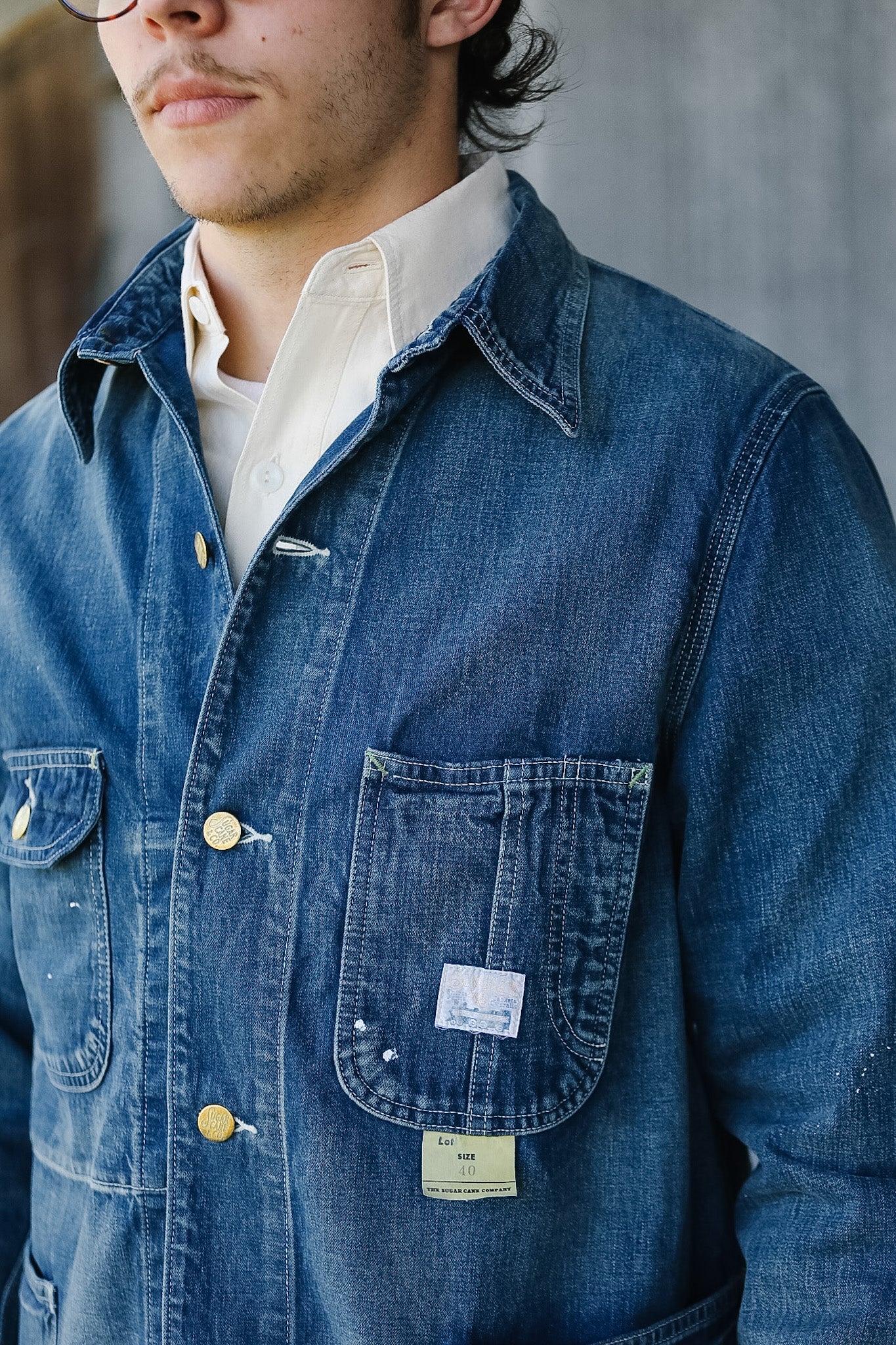 Close-up of a person wearing a blue denim jacket with a visible brand label.