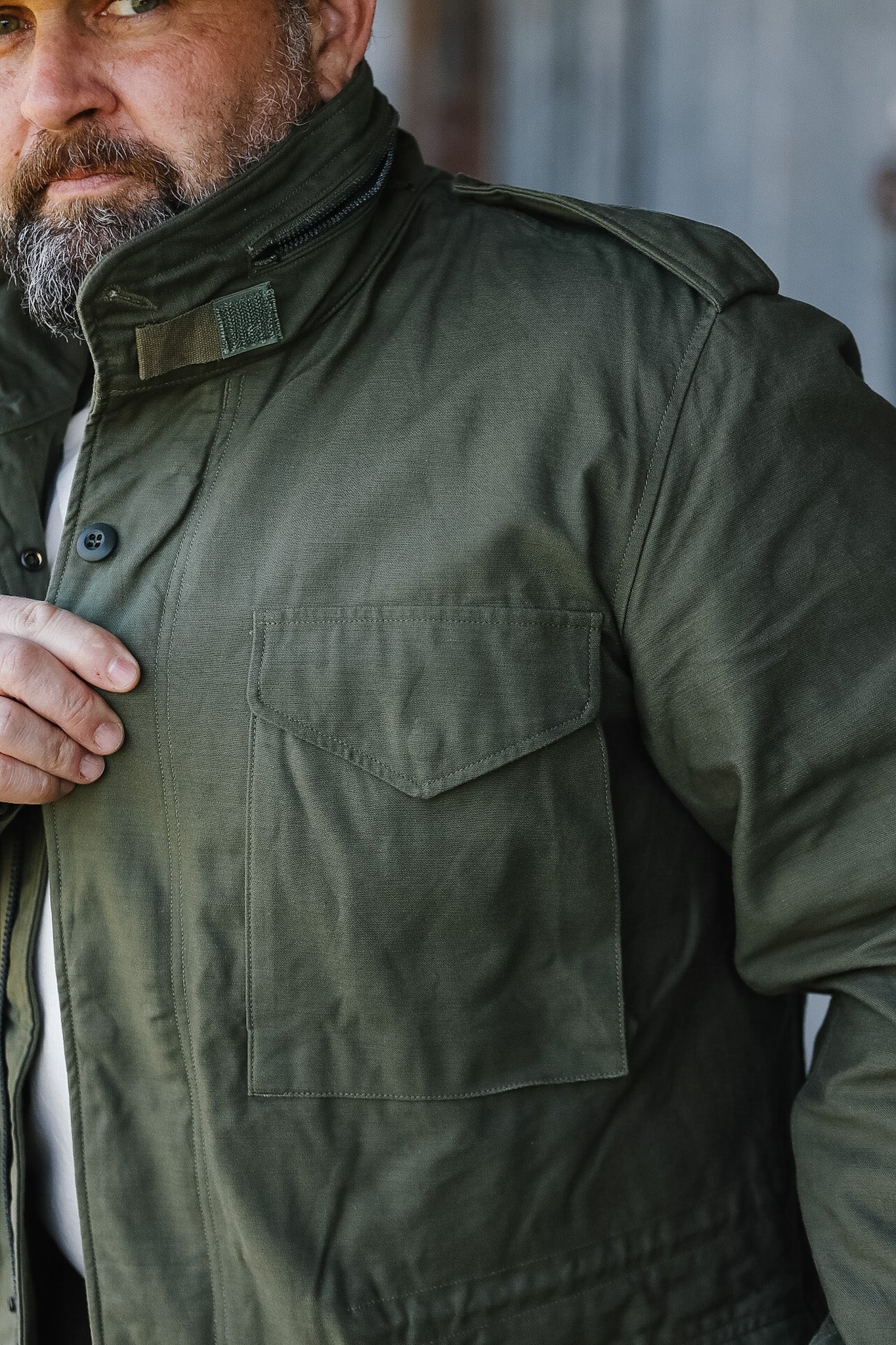 Man wearing a green jacket with a blurred background