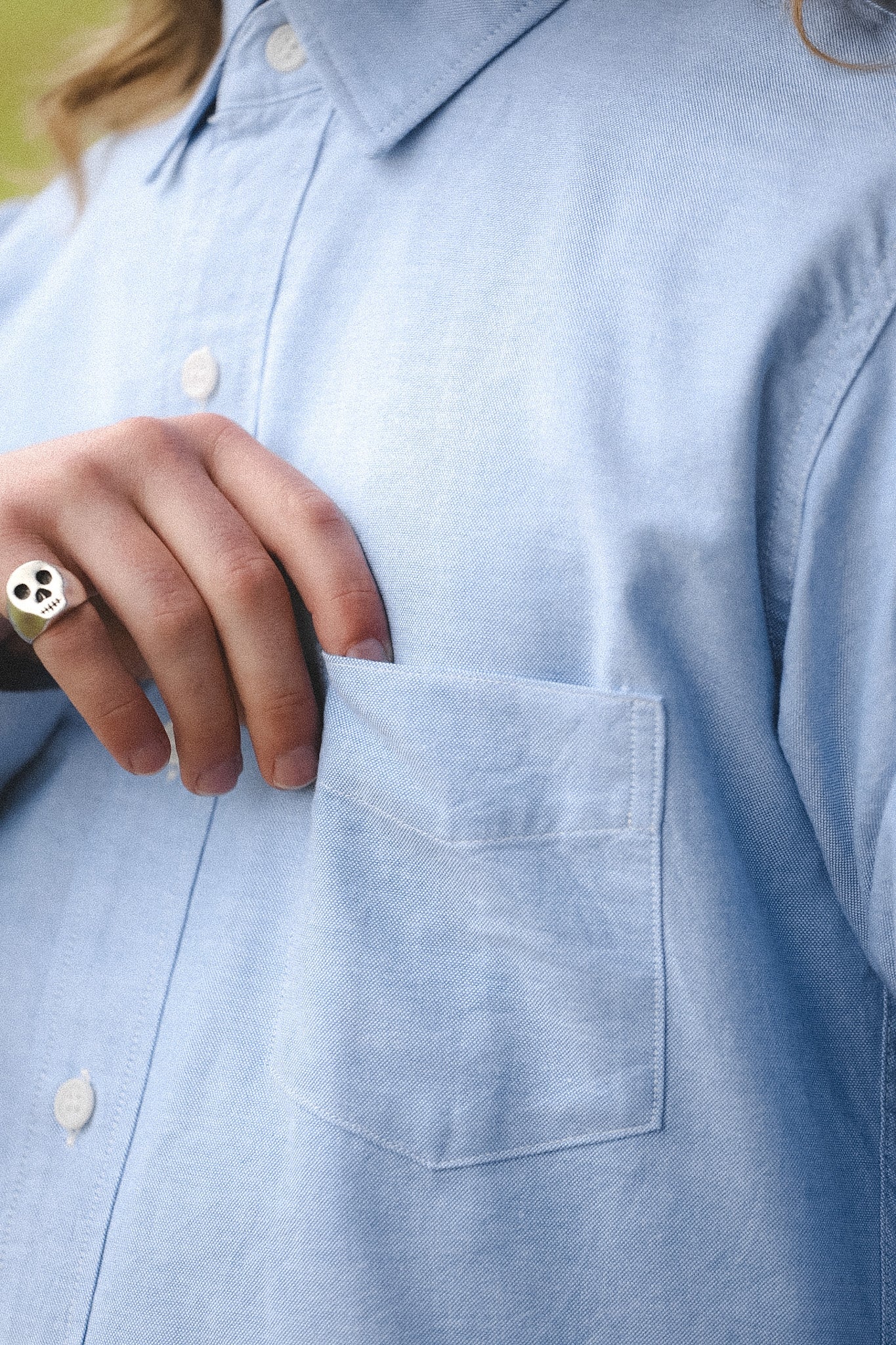 Close-up of a person wearing a light blue button-up shirt with a pocket.