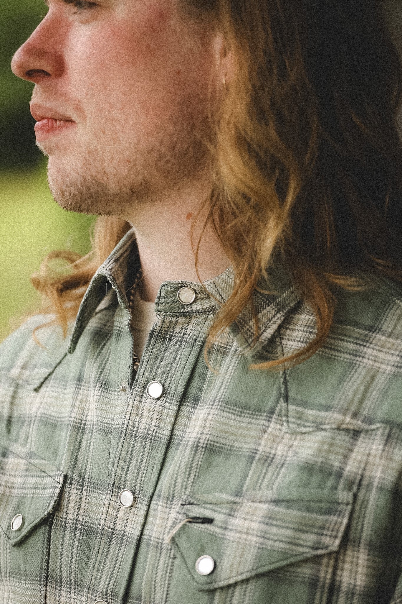 Person wearing a plaid shirt with a blurred background