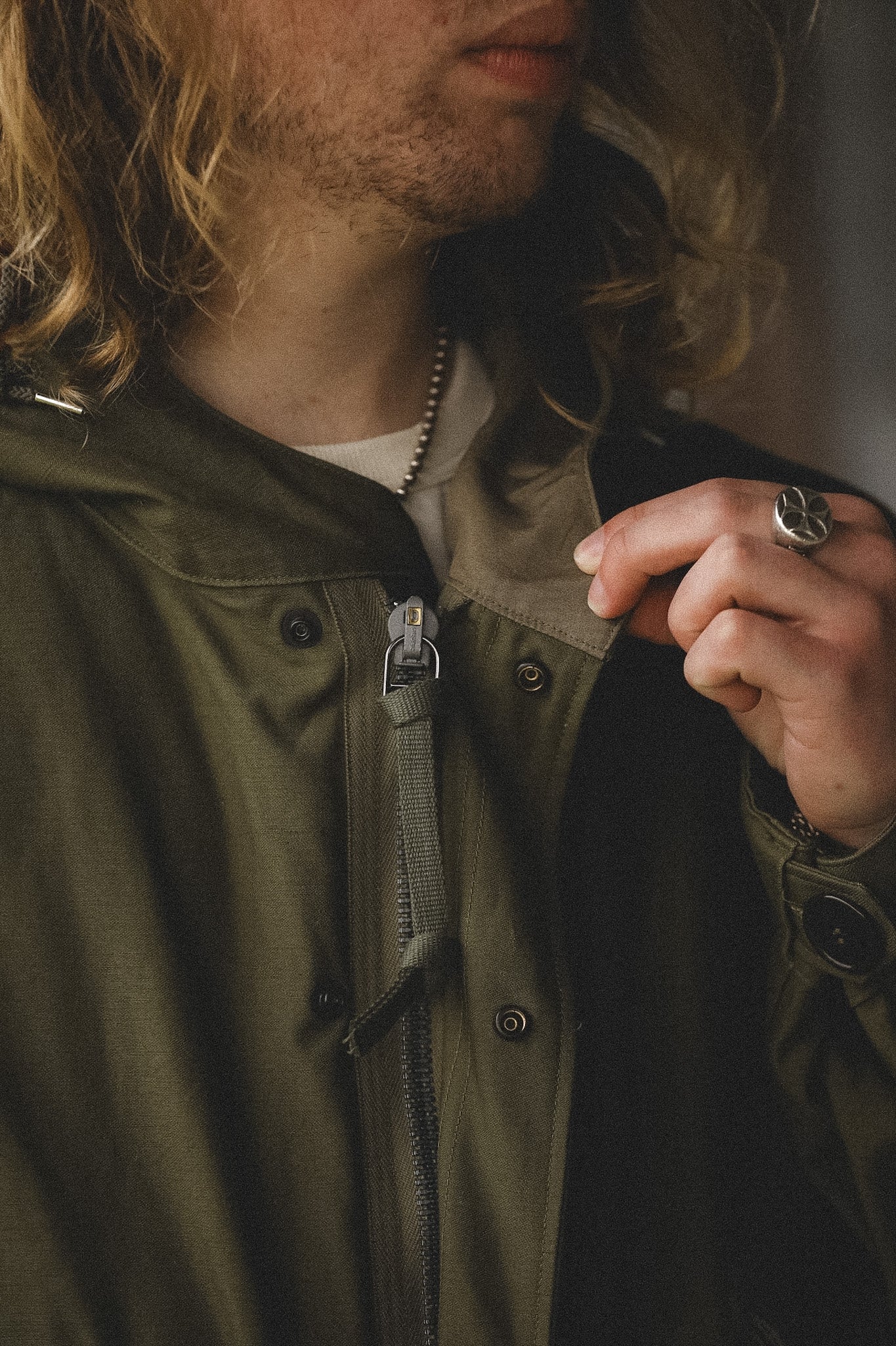 Person wearing a green jacket with a close-up of the zipper and collar.
