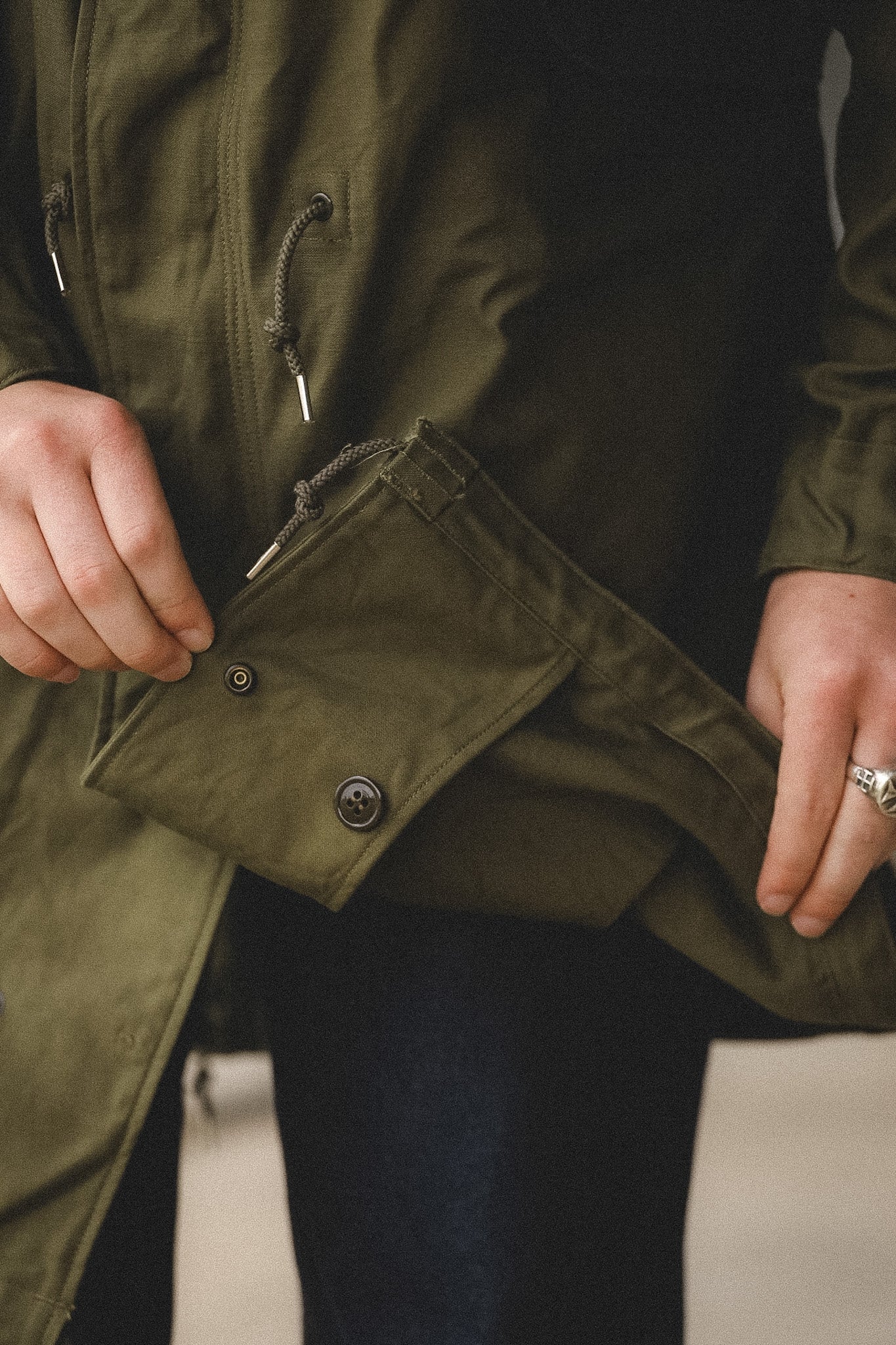 Person wearing a green jacket with a focus on the jacket's texture and buttons.