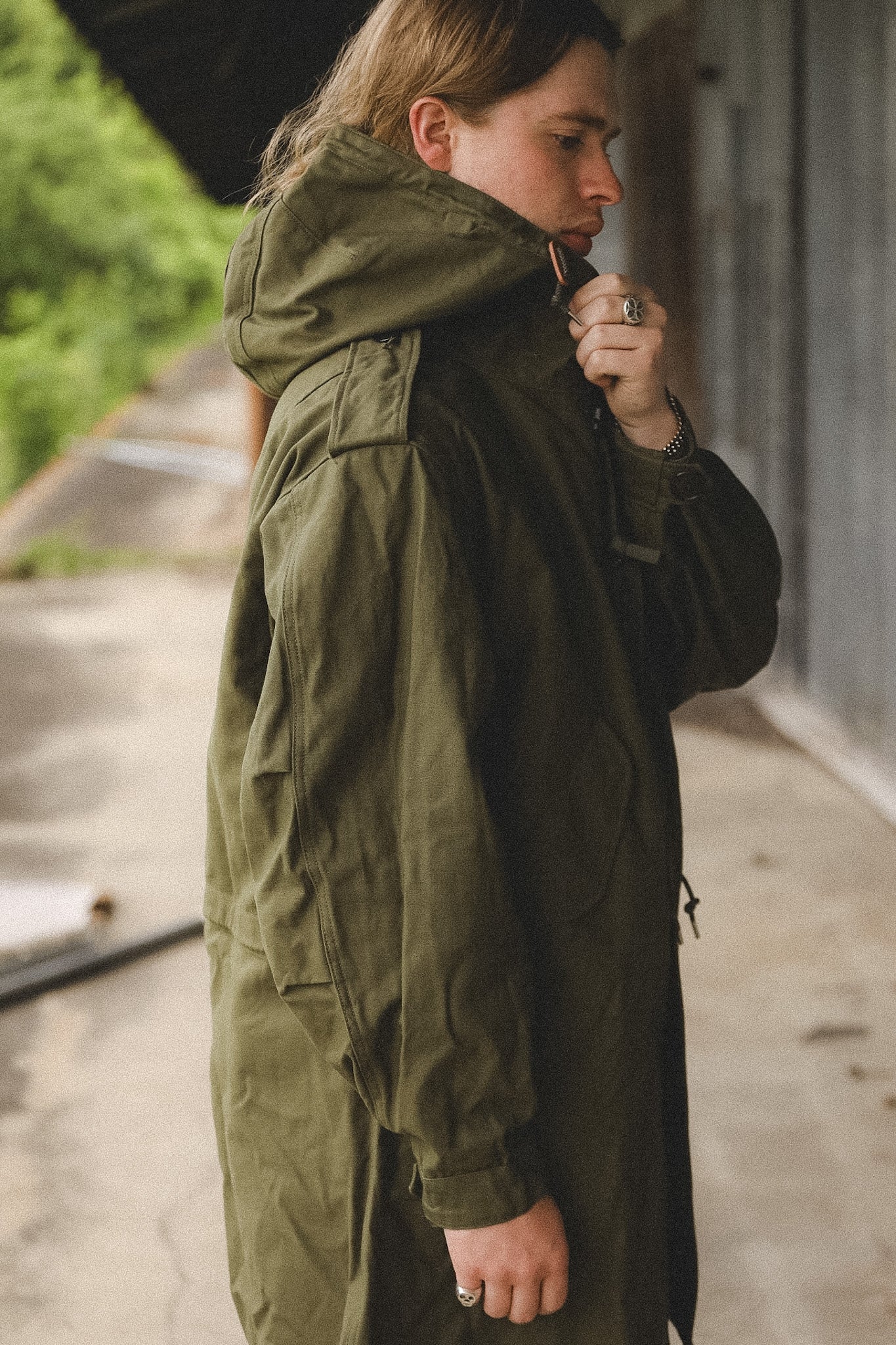 Person wearing a green parka standing on a sidewalk.