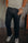 Man wearing black denim jeans and checkered slip-on sneakers indoors on industrial floor