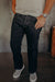 Man wearing black denim jeans and checkered slip-on sneakers indoors on industrial floor