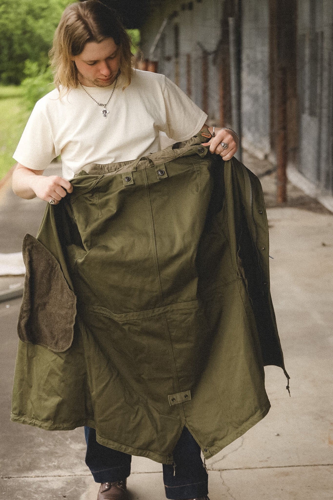 Person holding a green military-style jacket outdoors