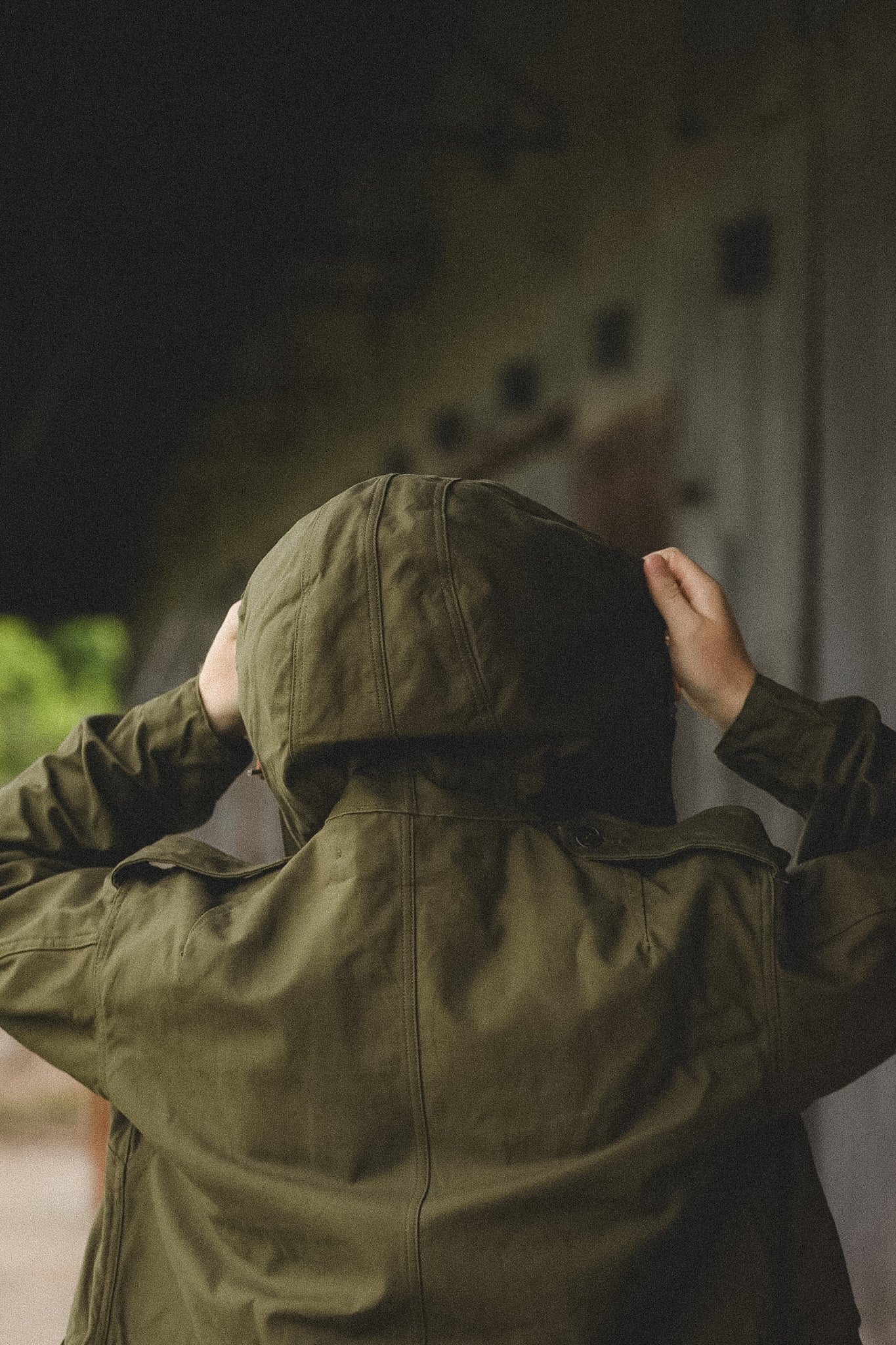 Person wearing a green raincoat with hood in an outdoor setting