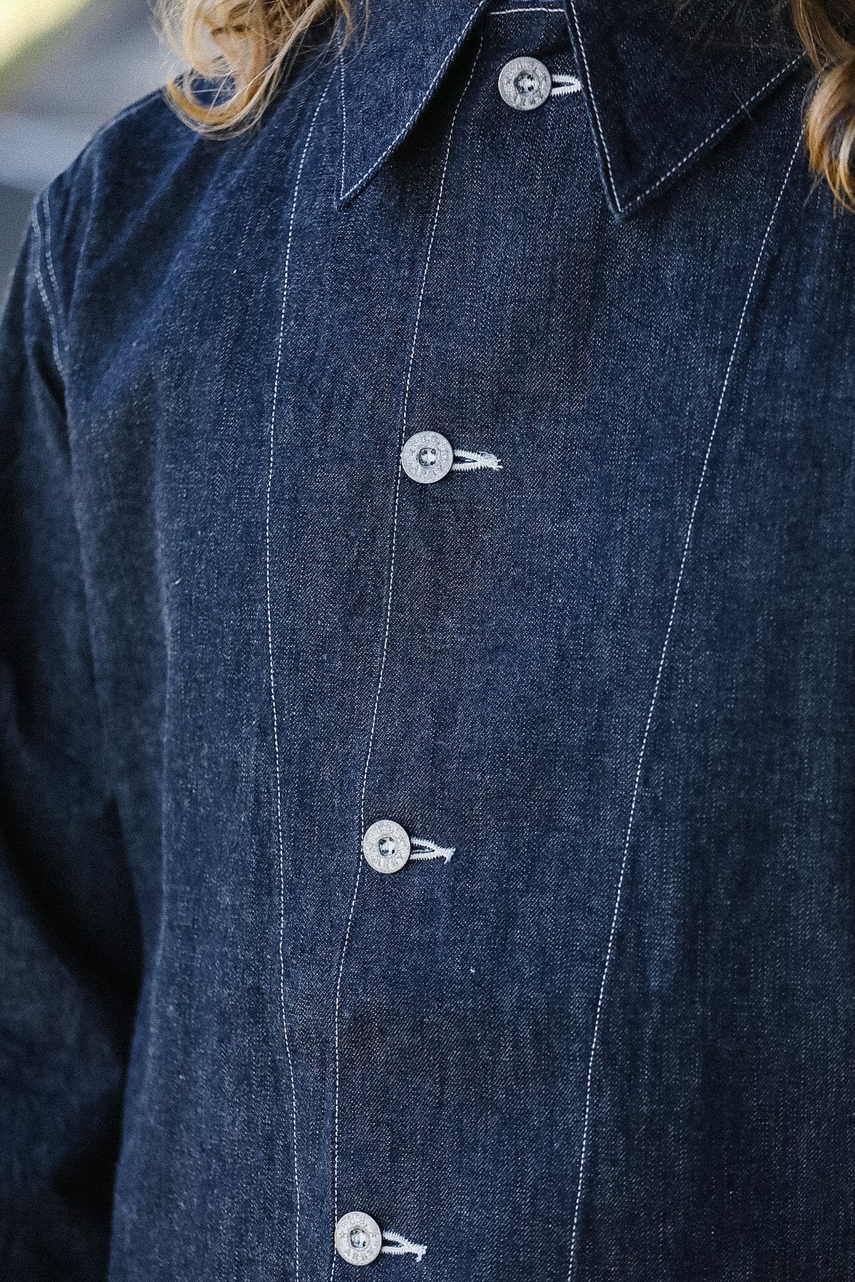 Close-up of a blue denim jacket with white buttons