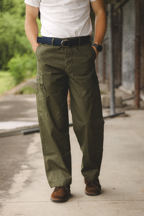 Person wearing green cargo pants and a white shirt outdoors.