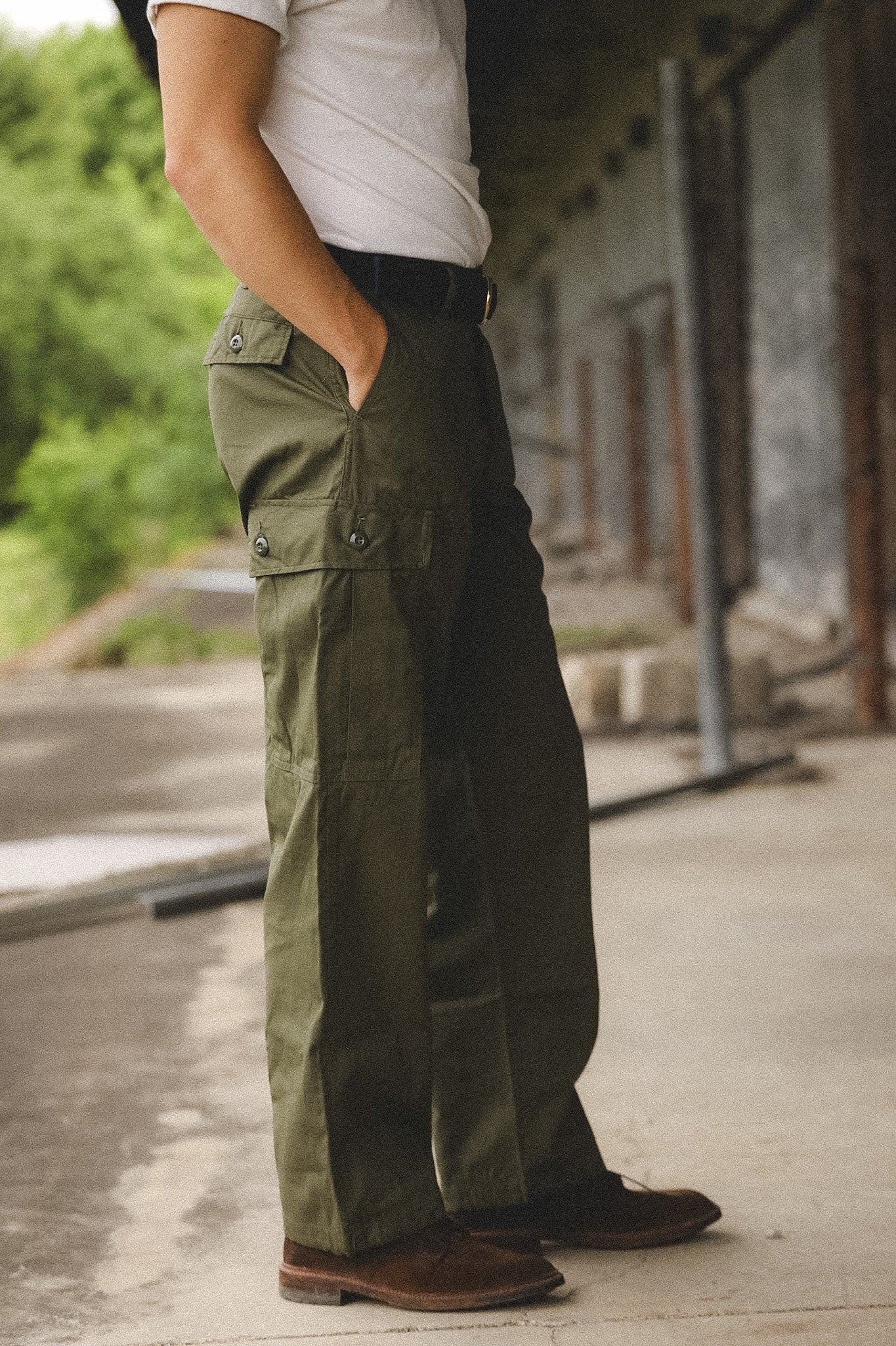 Person wearing olive green cargo pants and a white shirt in an outdoor setting.