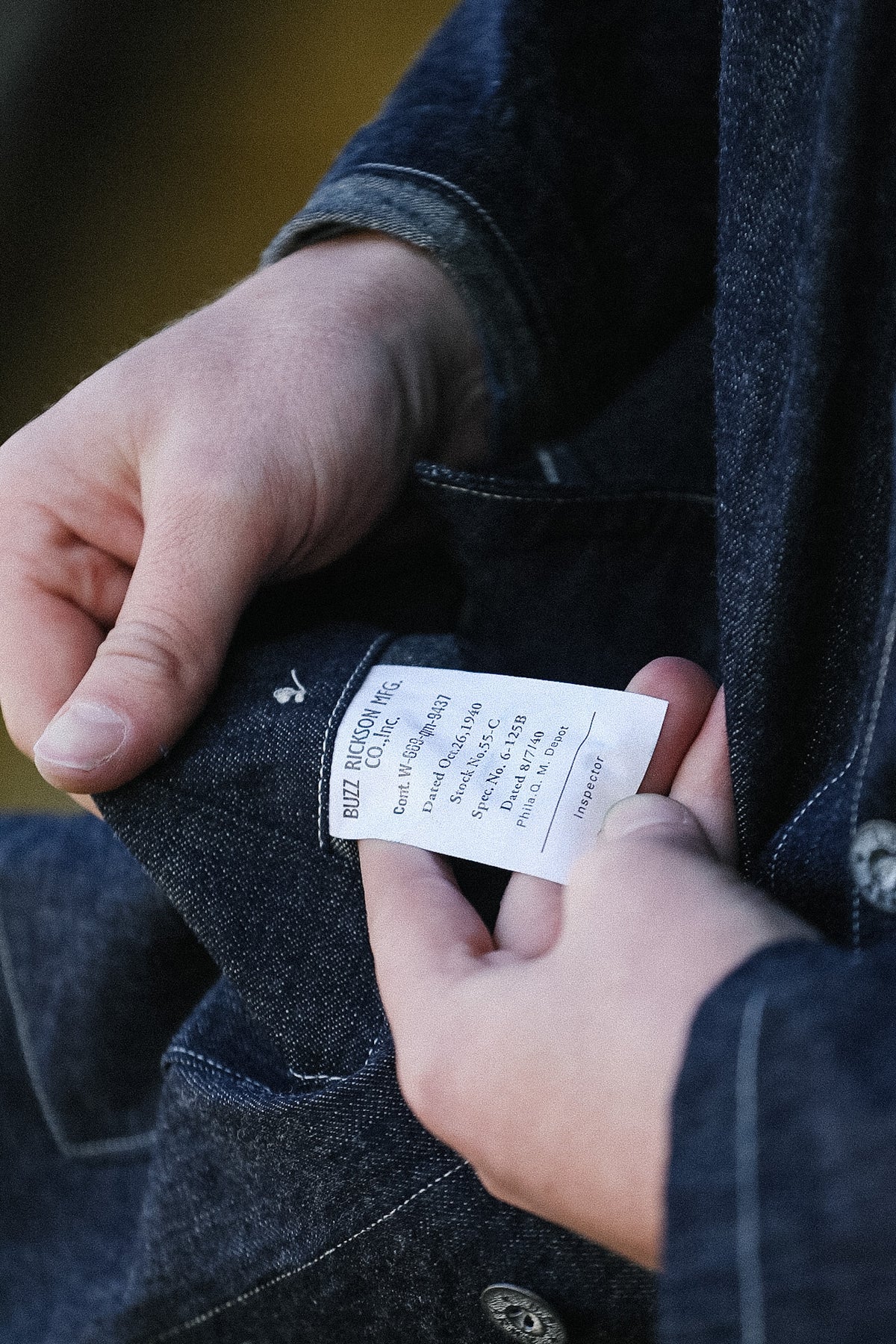 Person holding a clothing tag on a dark denim jacket