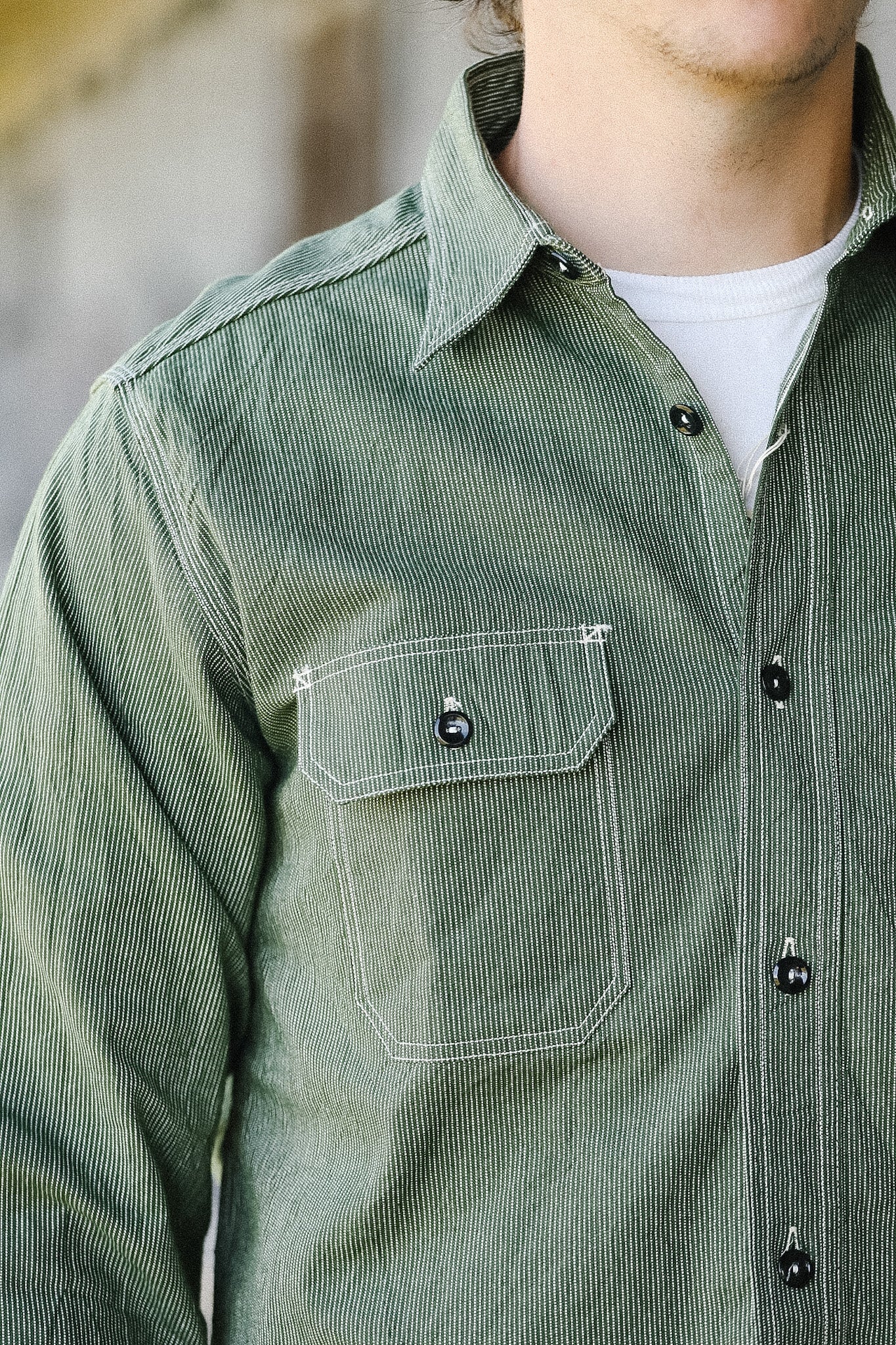 Green corduroy shirt with a pocket and buttons on a blurred background