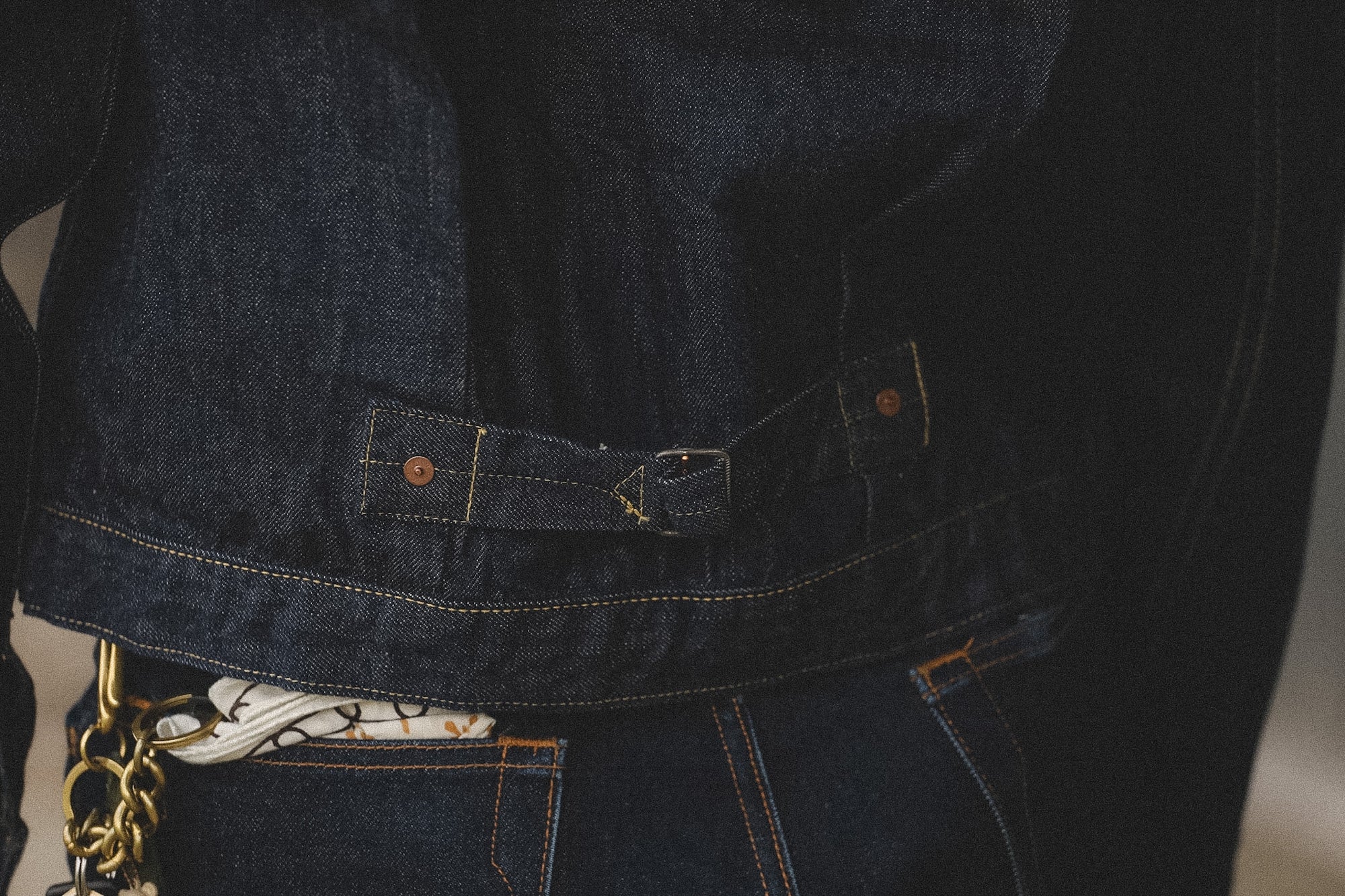 Close-up of a person wearing a dark denim jacket with a blurred background