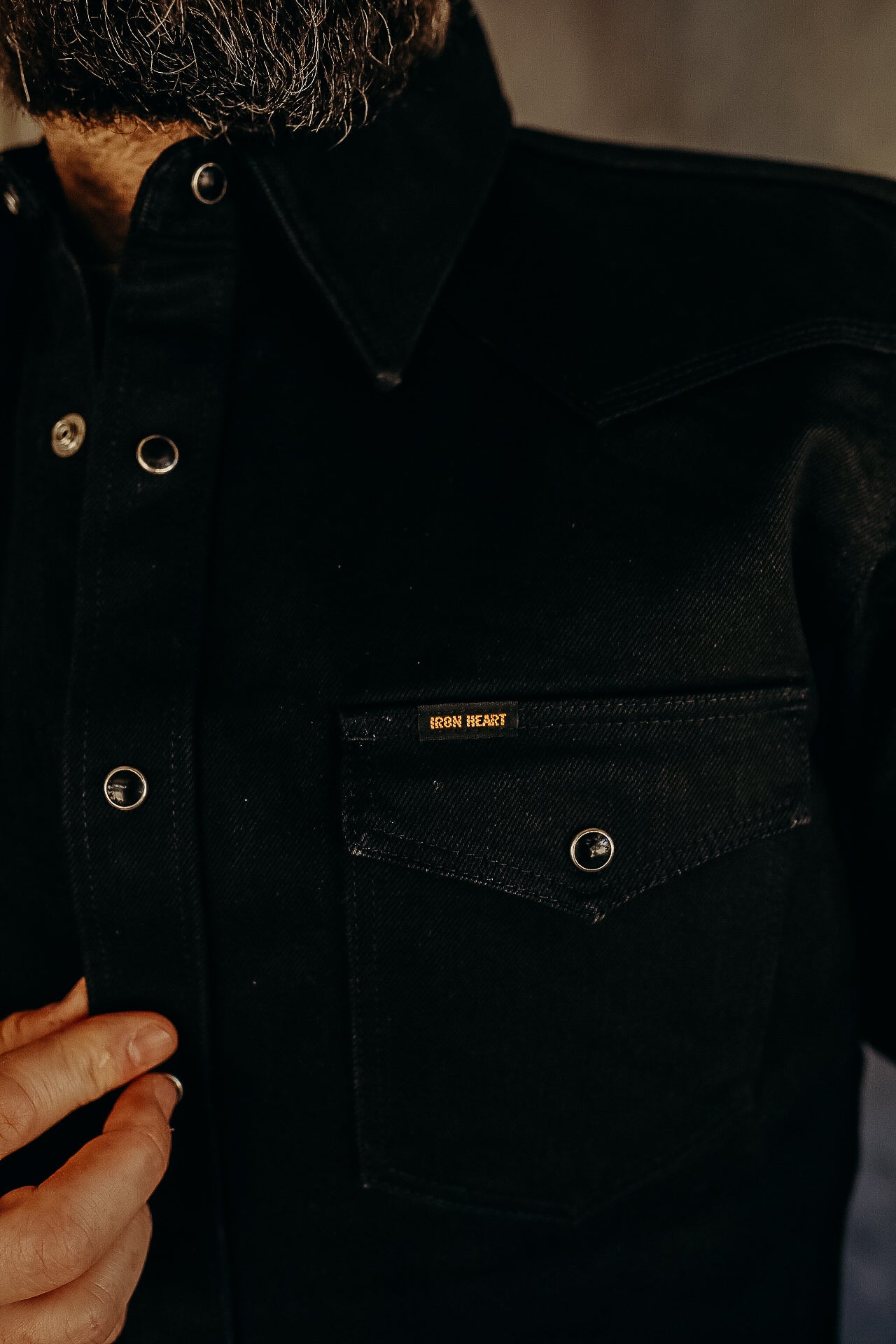 Close-up of black denim shirt with iron snap buttons and Iron Heart logo on chest pocket