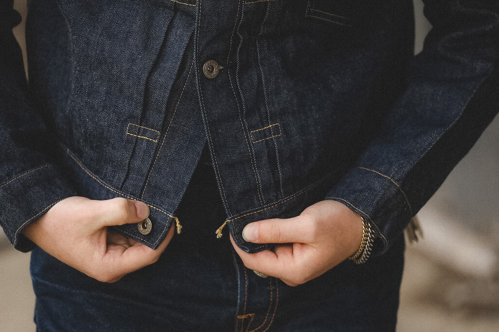 Close-up of a person wearing a dark denim jacket with visible stitching.