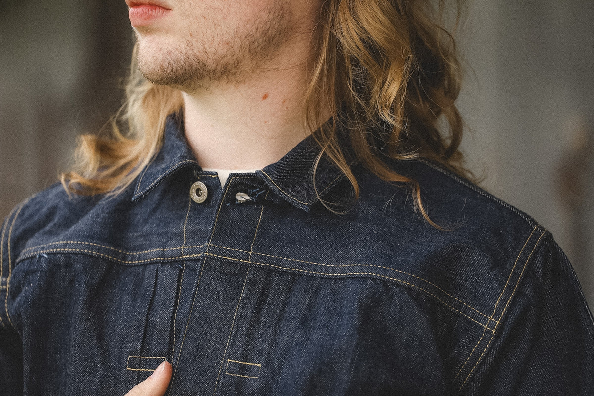 Person wearing a dark denim shirt with a blurred background