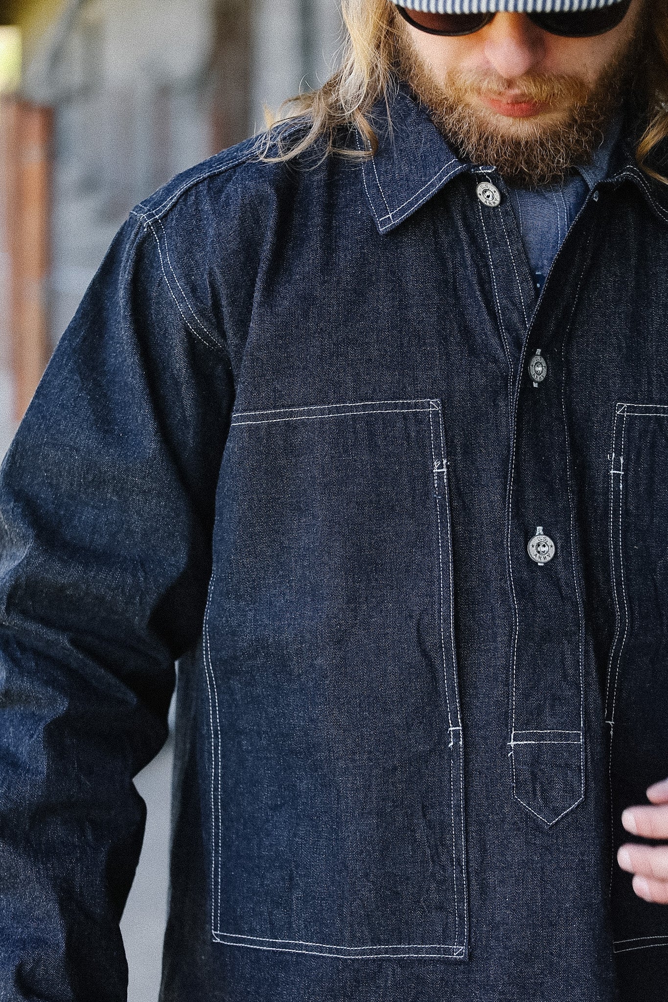 Man wearing a dark denim jacket with a blurred background