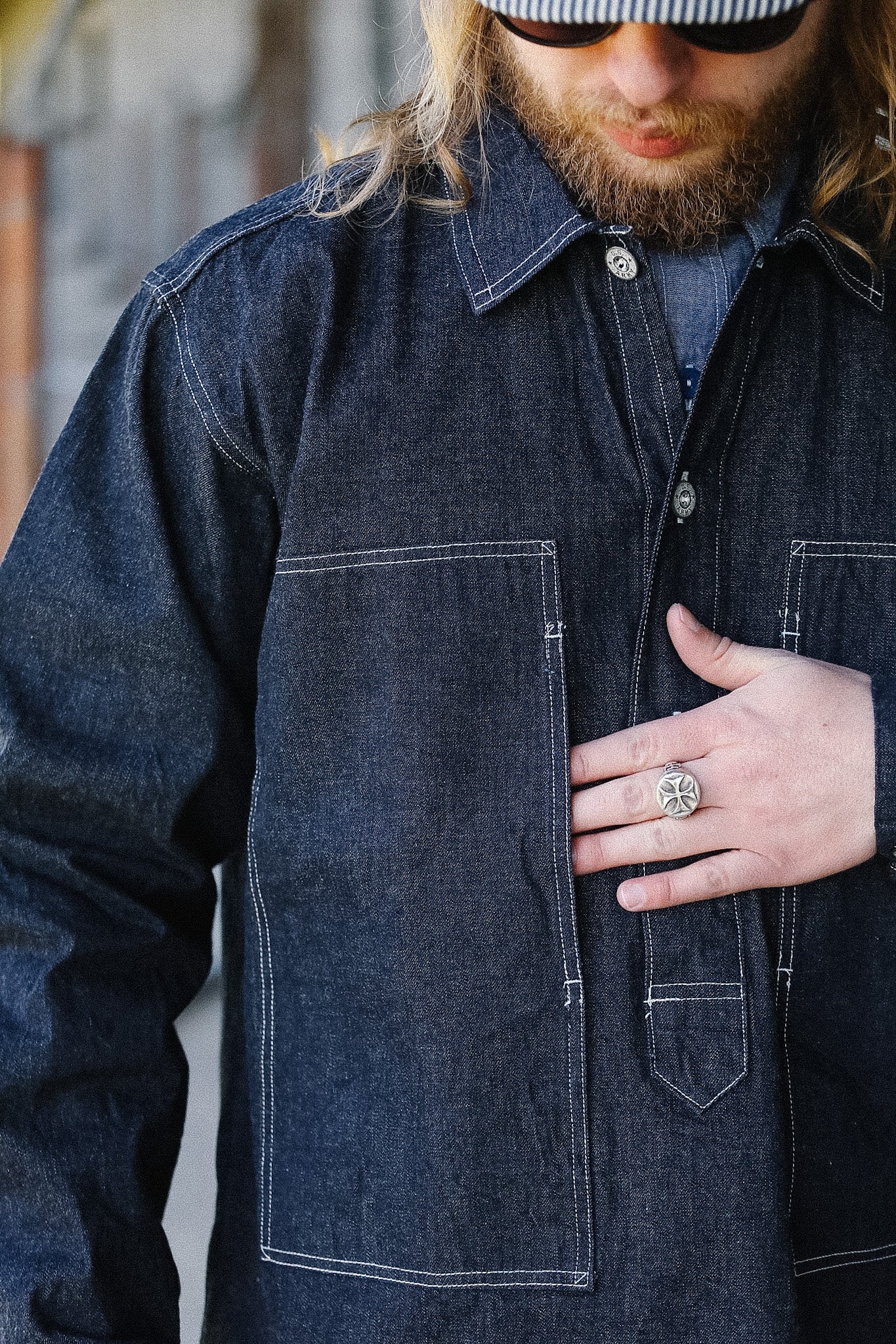 Man wearing a dark denim jacket with a blurred background