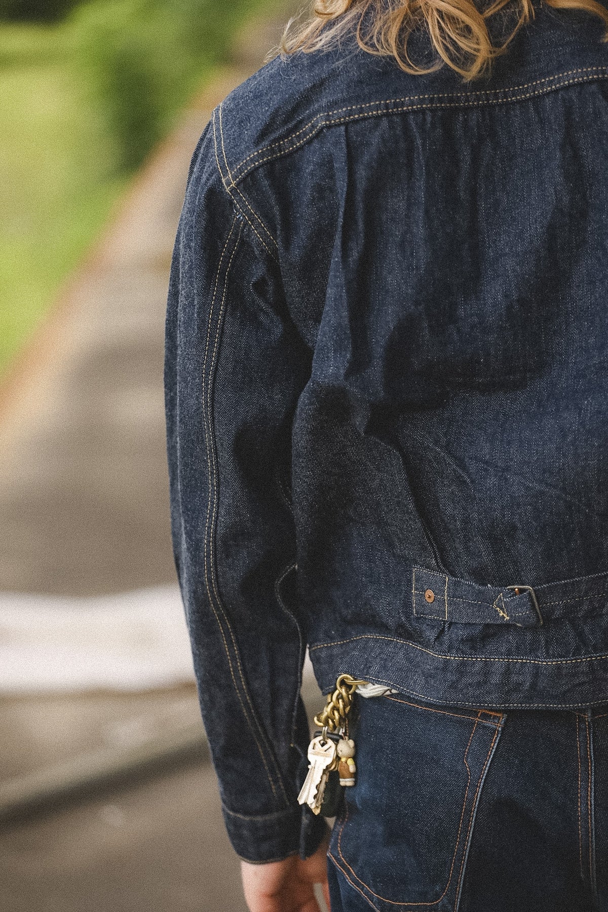 Person wearing a blue denim jacket with keys hanging from the pocket, blurred background
