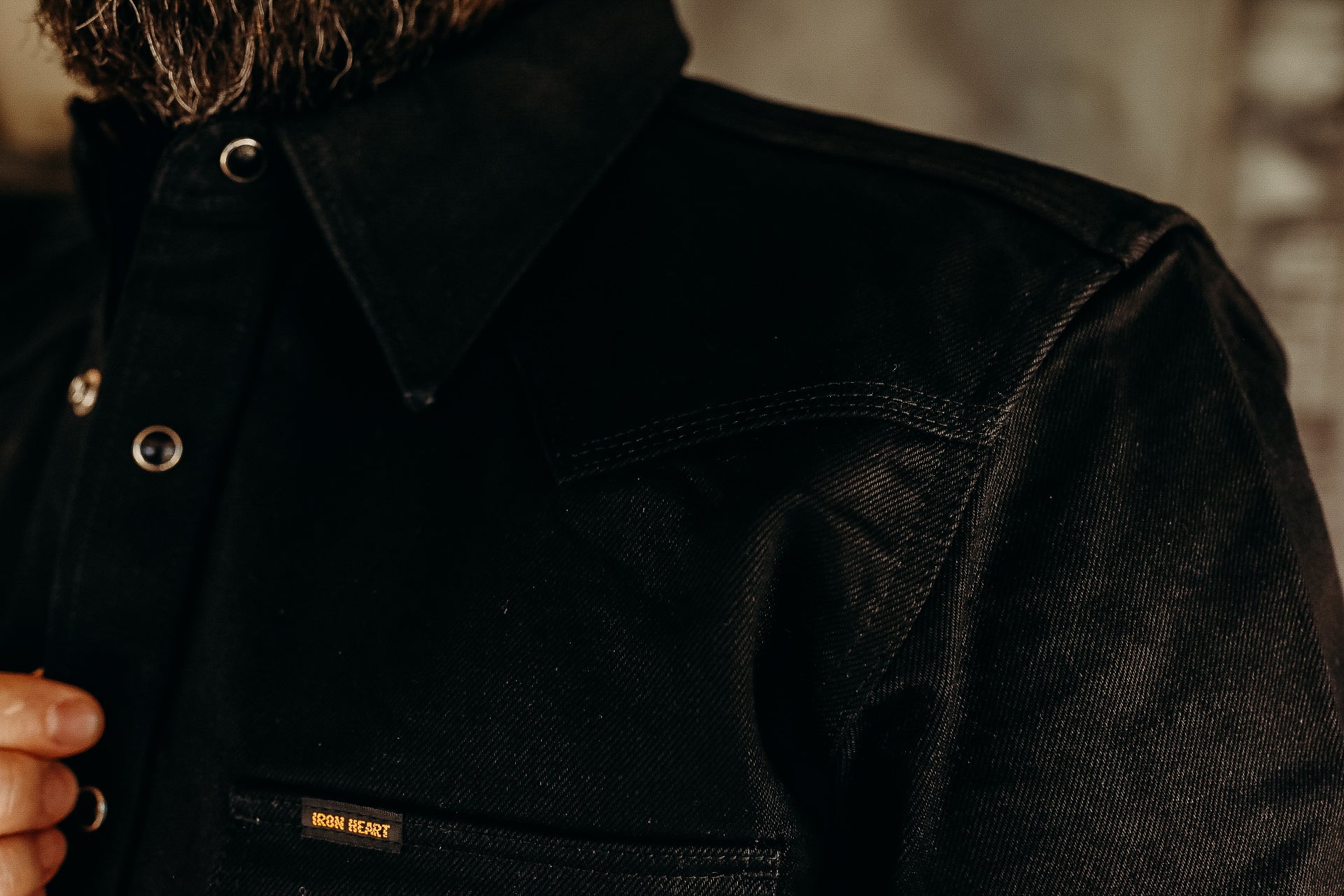 Close-up of a black Iron Heart denim jacket with metal snap buttons and a collar