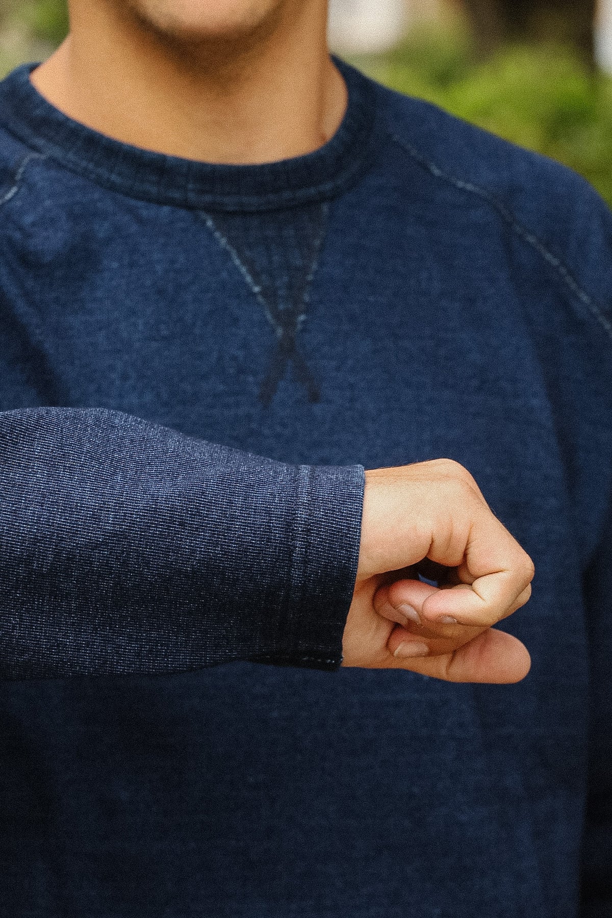 detail shot of a textured blue shirt with a green foliage background. 