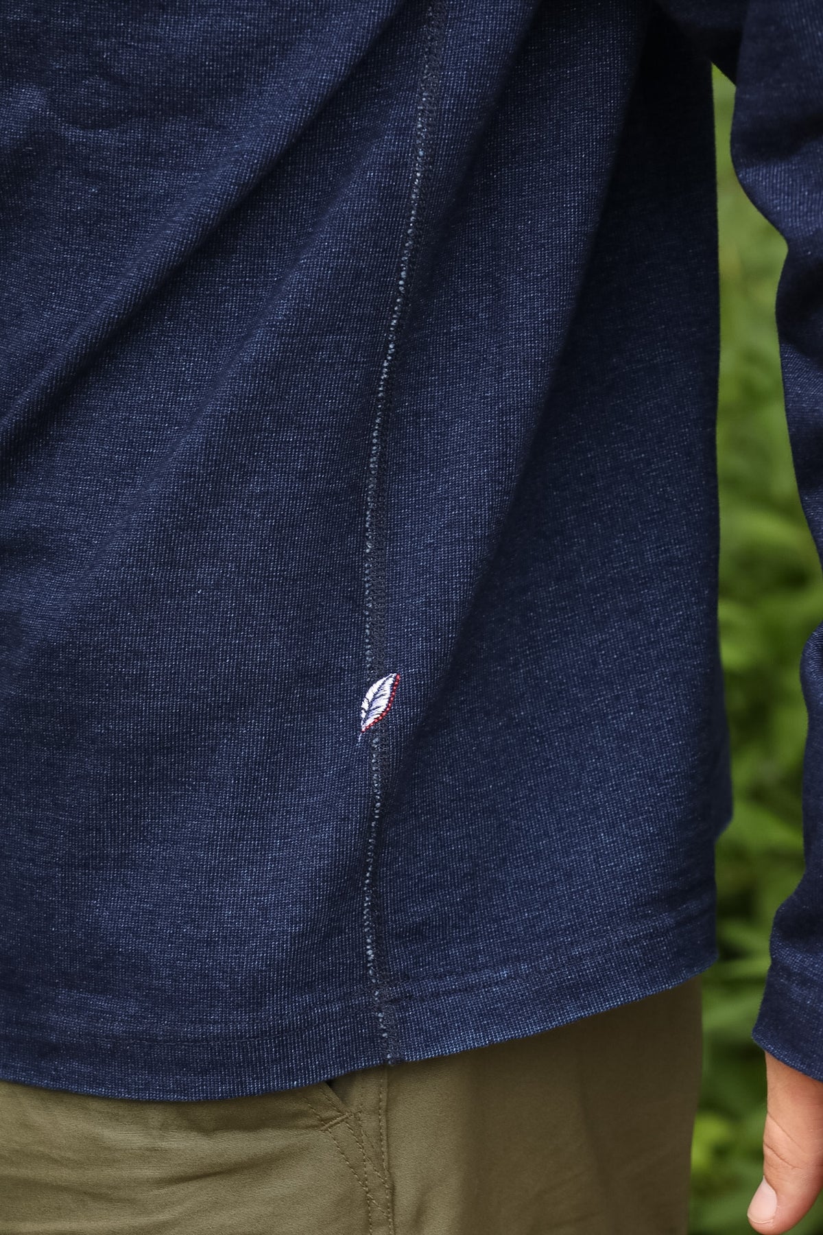 detail shot of a textured blue shirt with a green foliage background. 