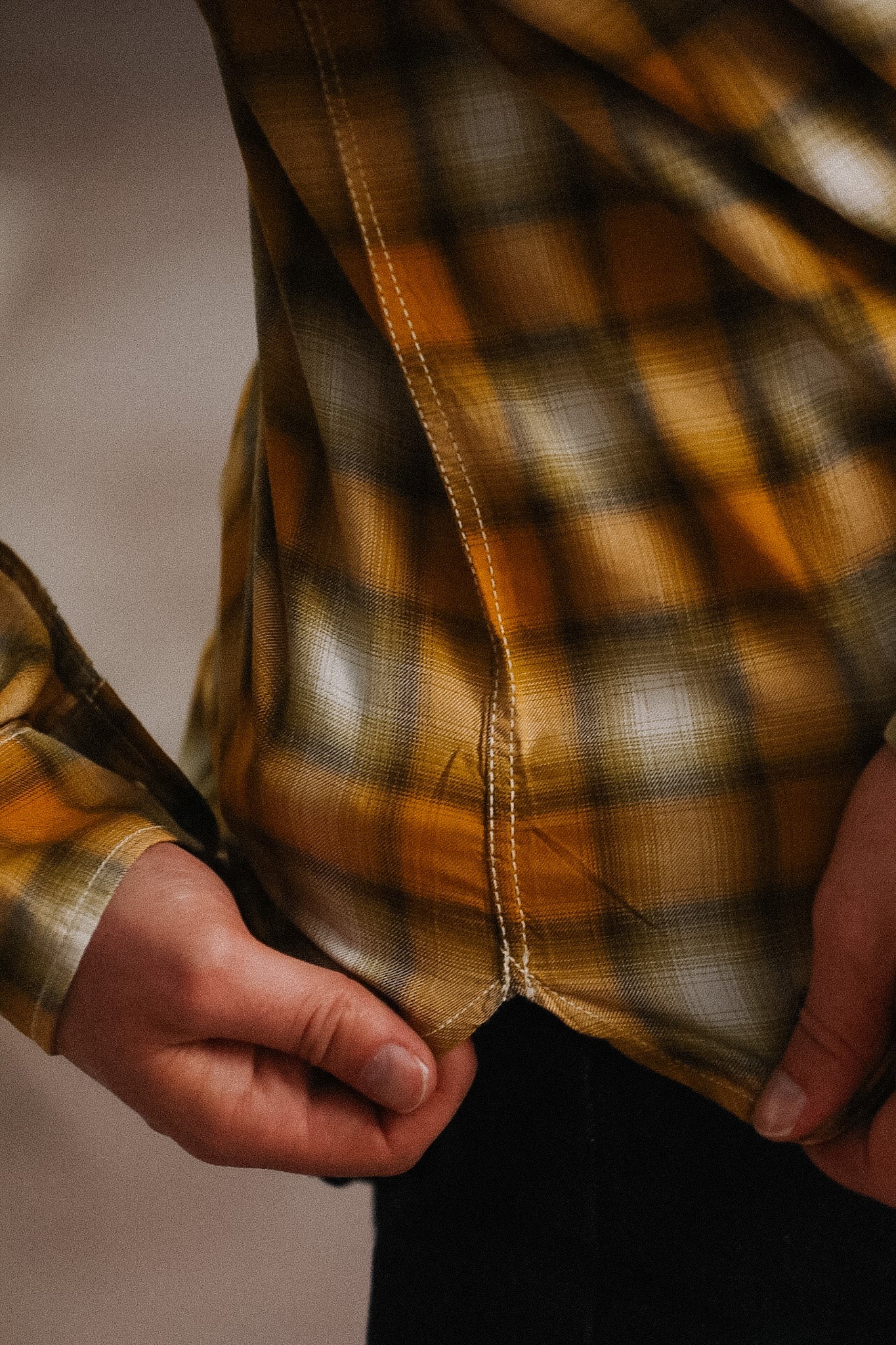 Close-up of a person wearing a plaid shirt with a blurred background