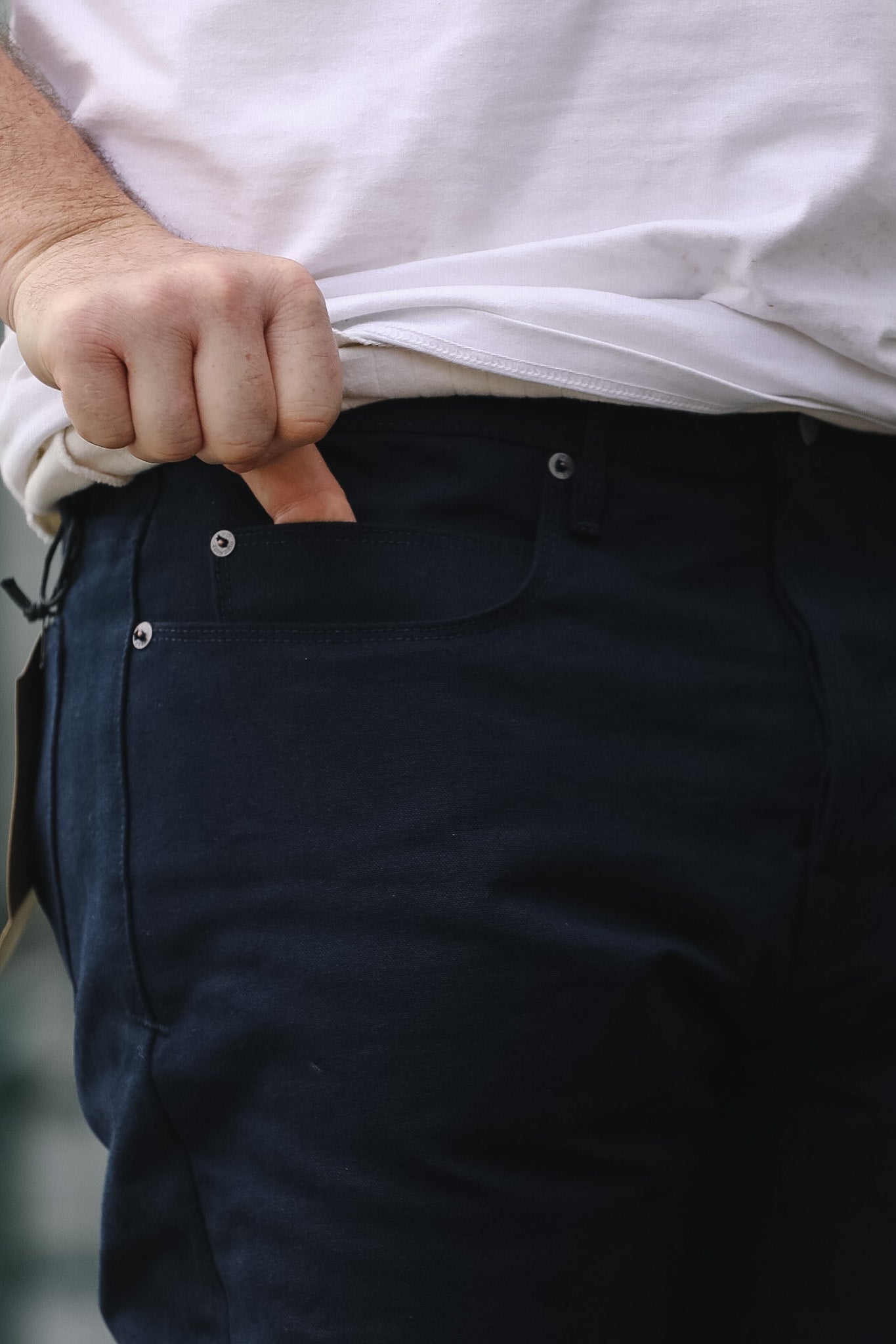 Person wearing navy pants with a white shirt, focusing on the waist area.