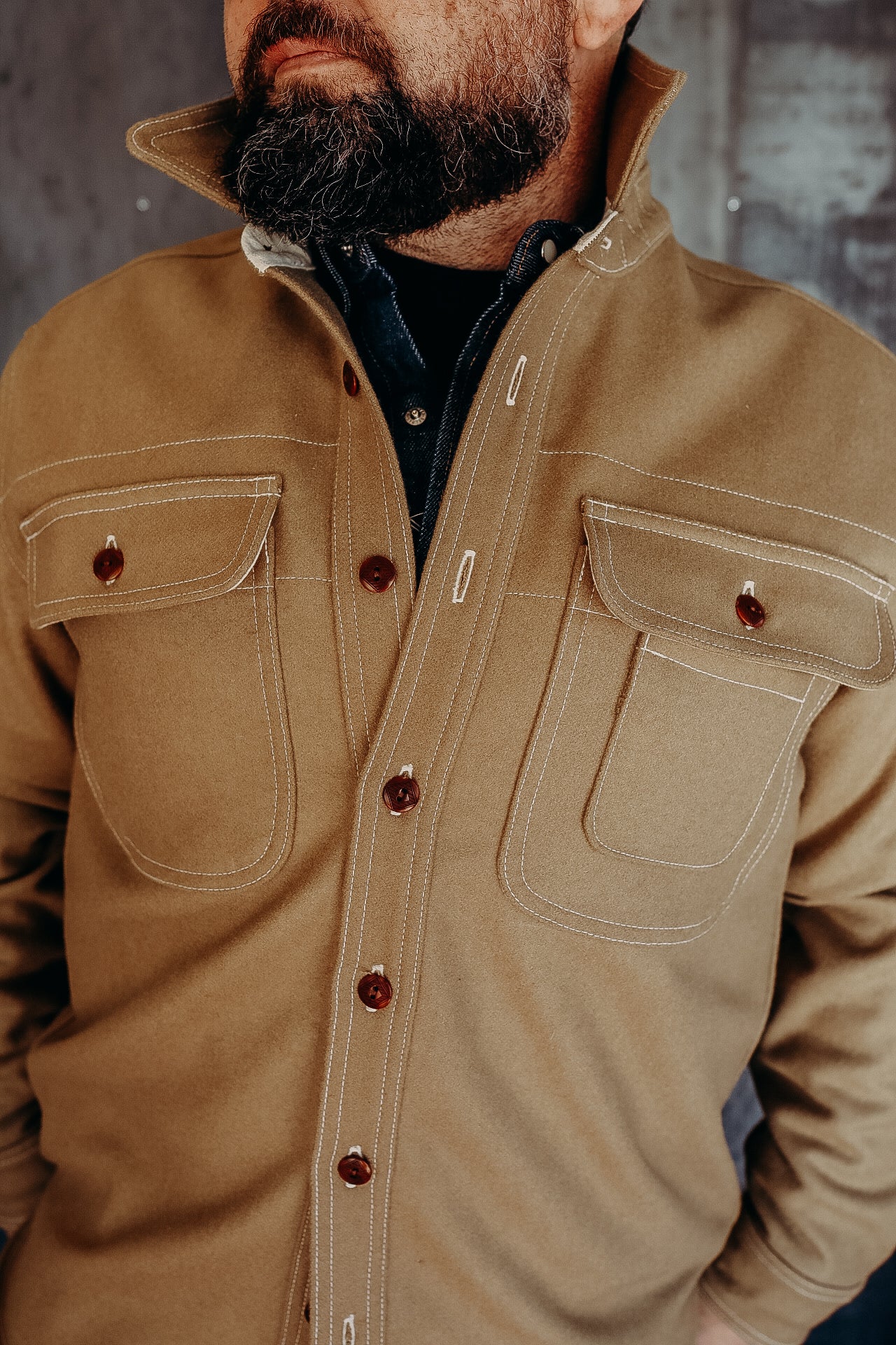 Close-up of a man wearing a brown button-up work shirt with chest pockets and contrast stitching at Iron Shop Provisions