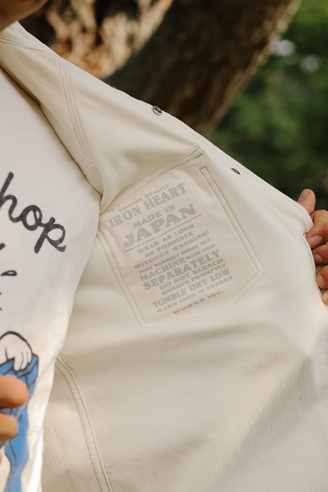 Close-up of a white denim jacket with branding text on the back pocket.