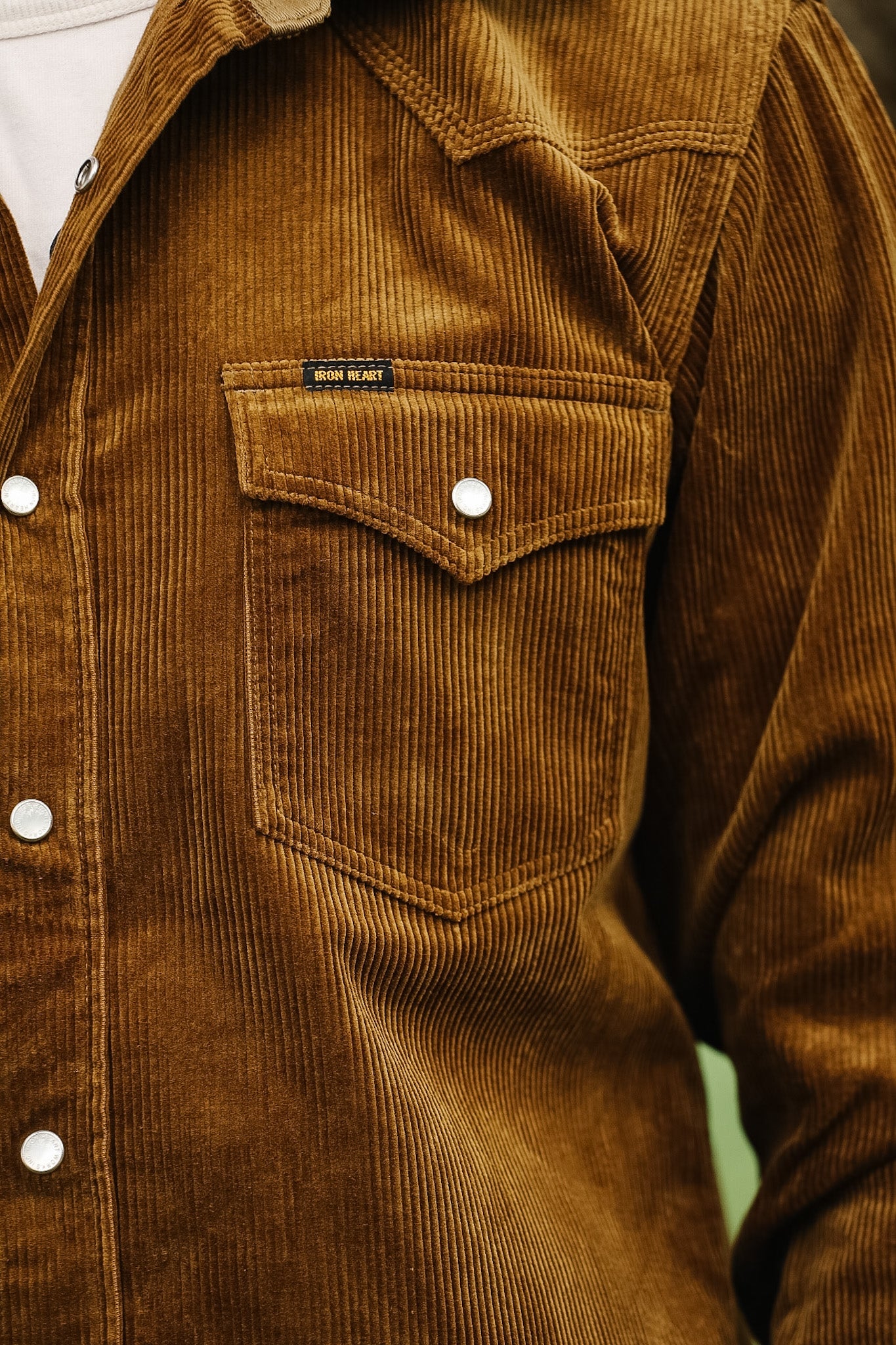 Close-up of a brown corduroy shirt and blue jeans with a blurred background