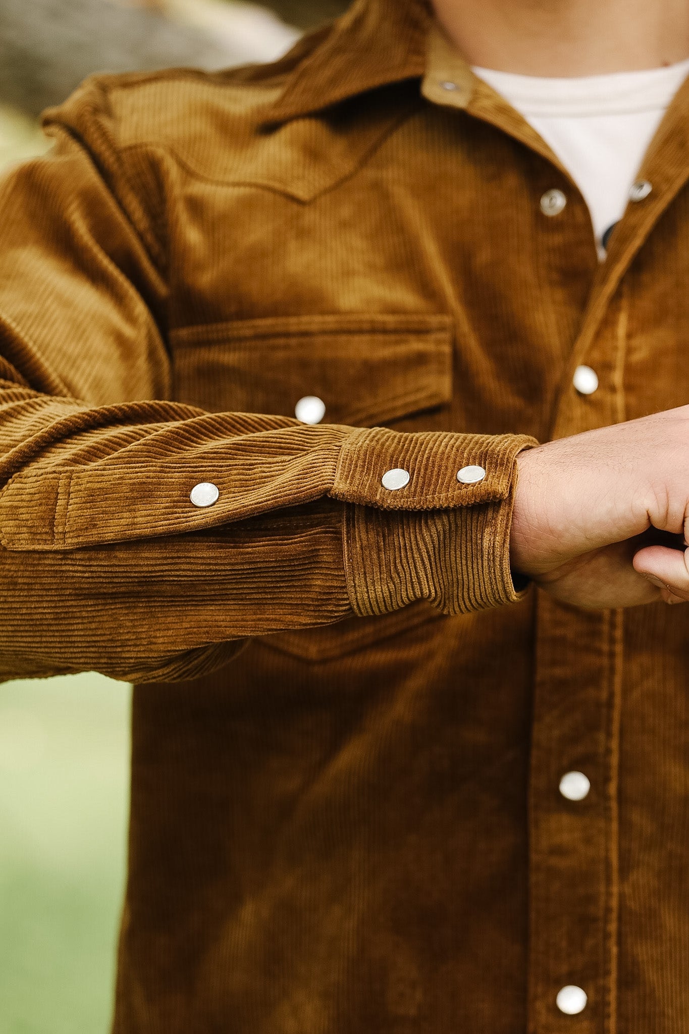 Close-up of a brown corduroy shirt and blue jeans with a blurred background