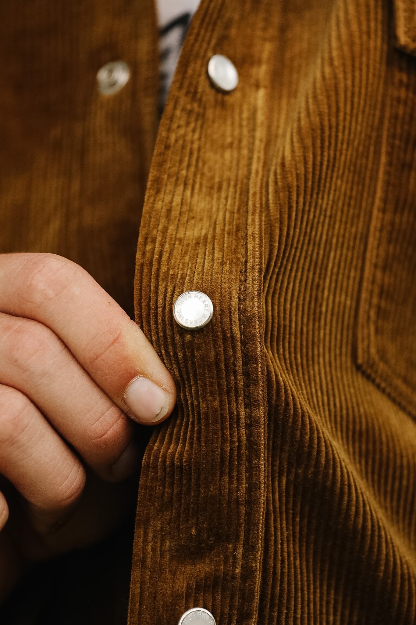 Close-up of a brown corduroy shirt and blue jeans with a blurred background