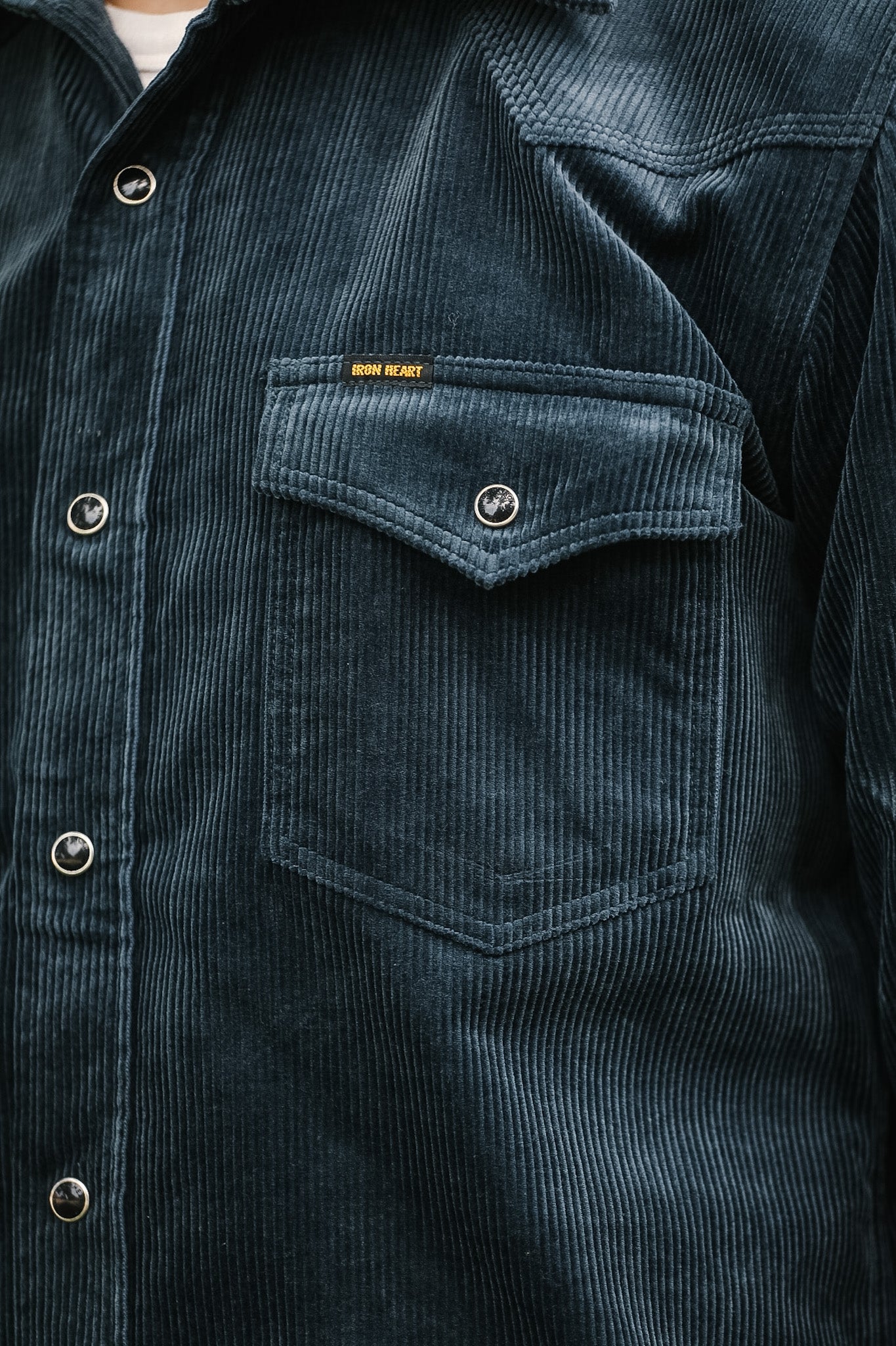 Dark blue corduroy shirt with a pocket and visible brand name.