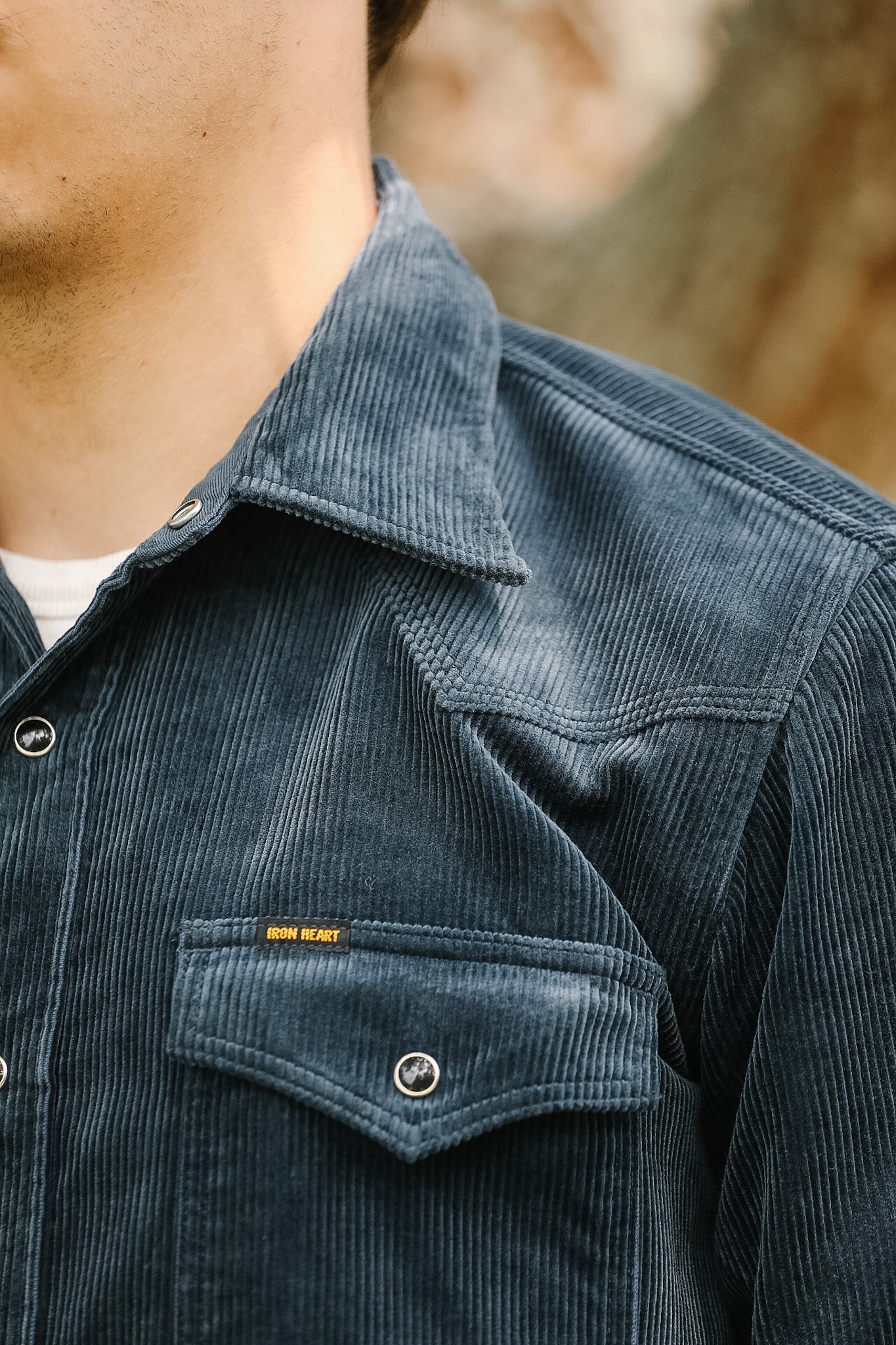 Close-up of a person wearing a dark blue corduroy shirt with a blurred background