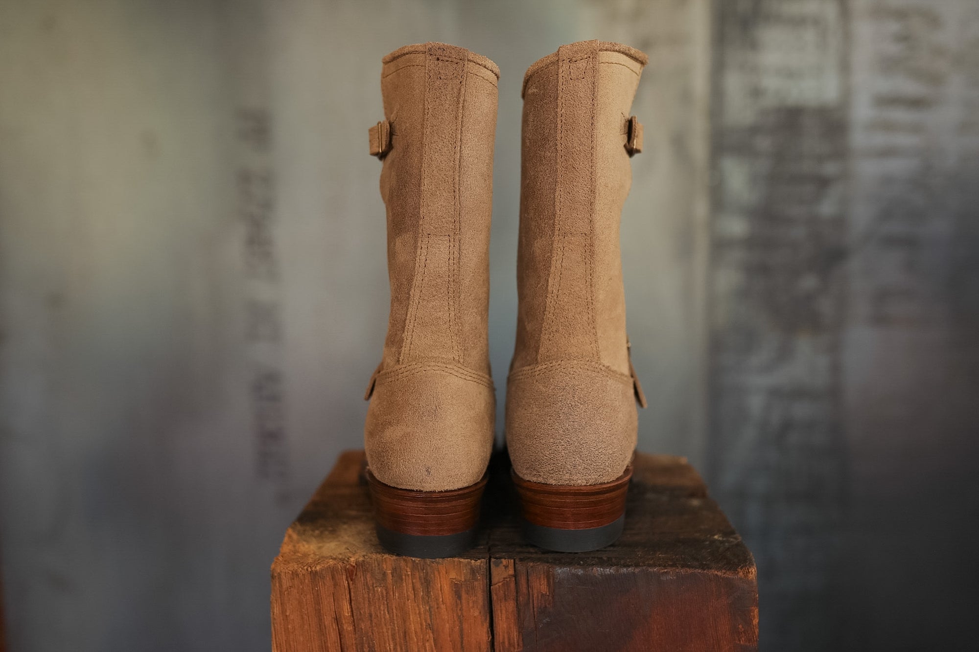 Pair of brown boots on a wooden block with a textured wall background