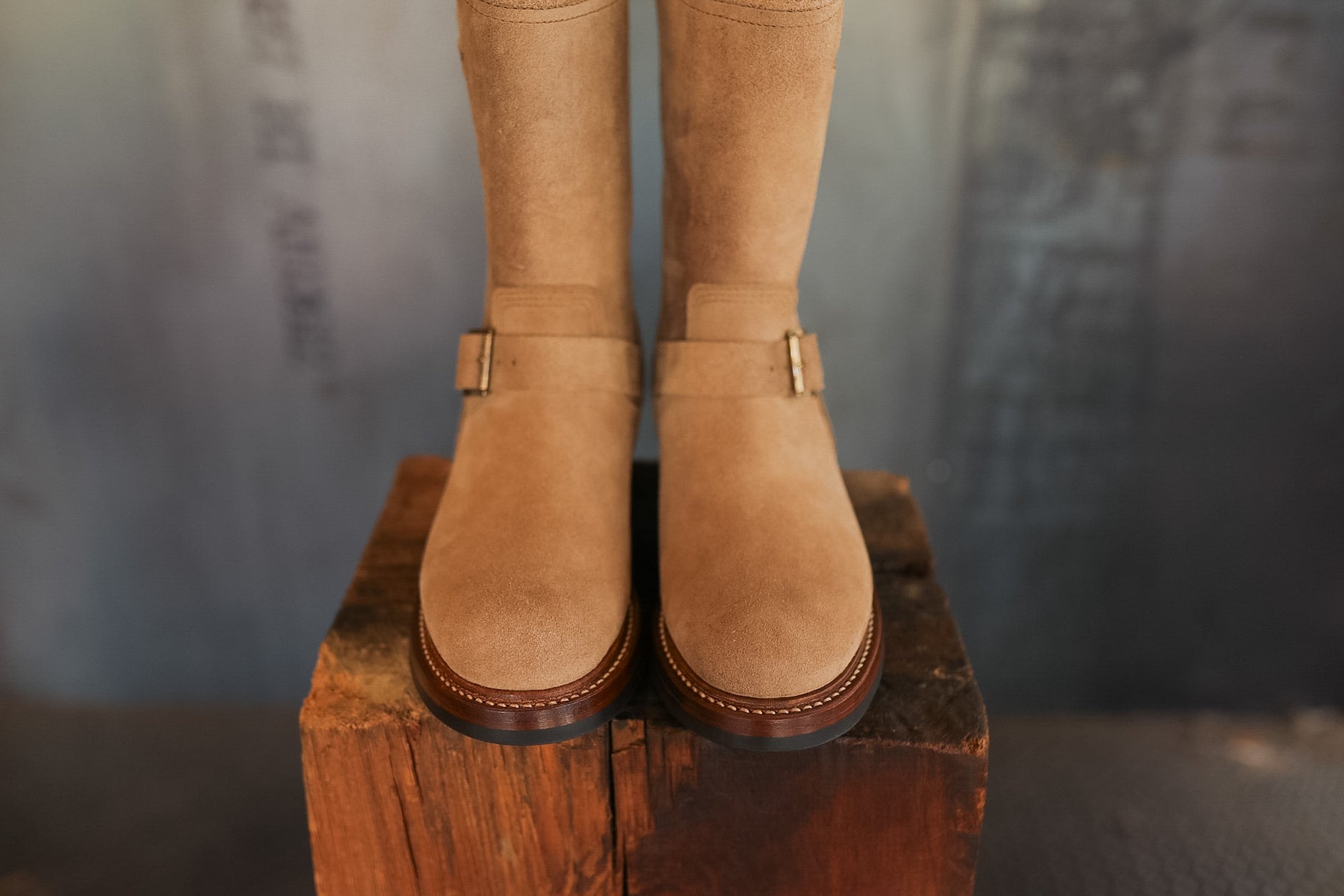 Pair of tan boots on a wooden block with a blurred background