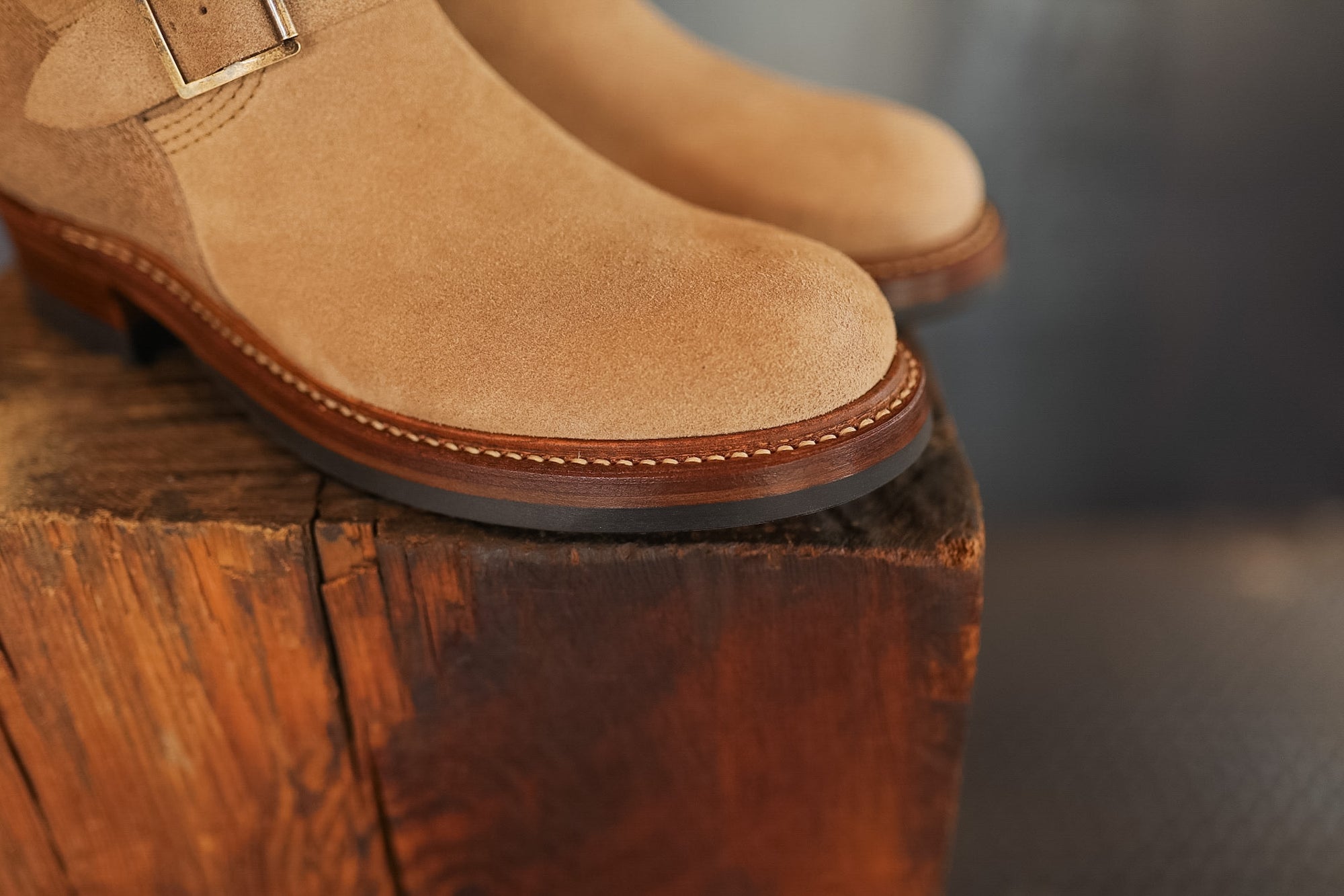 Pair of tan suede boots on a wooden block with a blurred background