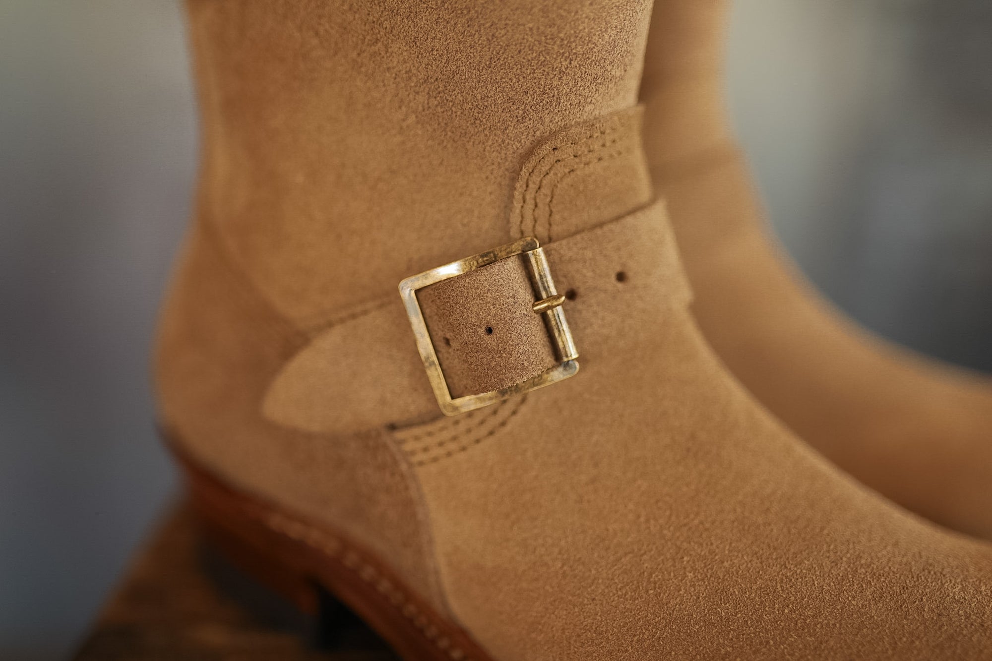 Close-up of a brown boot with a gold buckle on a blurred background