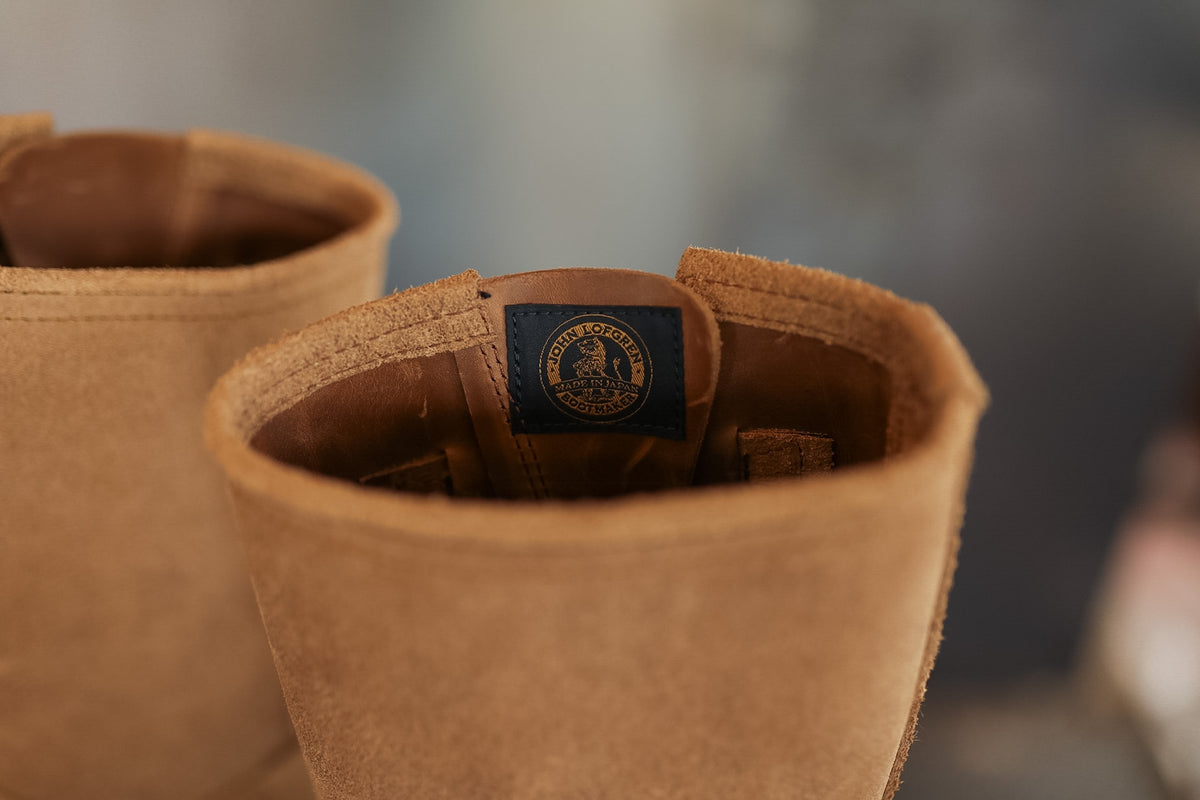Close-up of brown leather boots with a brand label on a blurred background