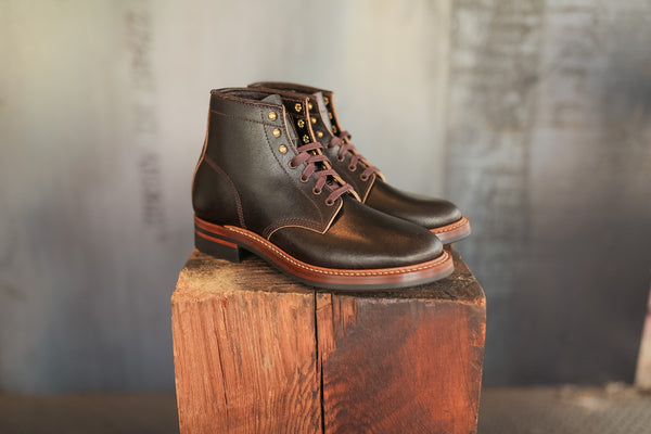 Pair of brown leather boots on a wooden block with a textured background