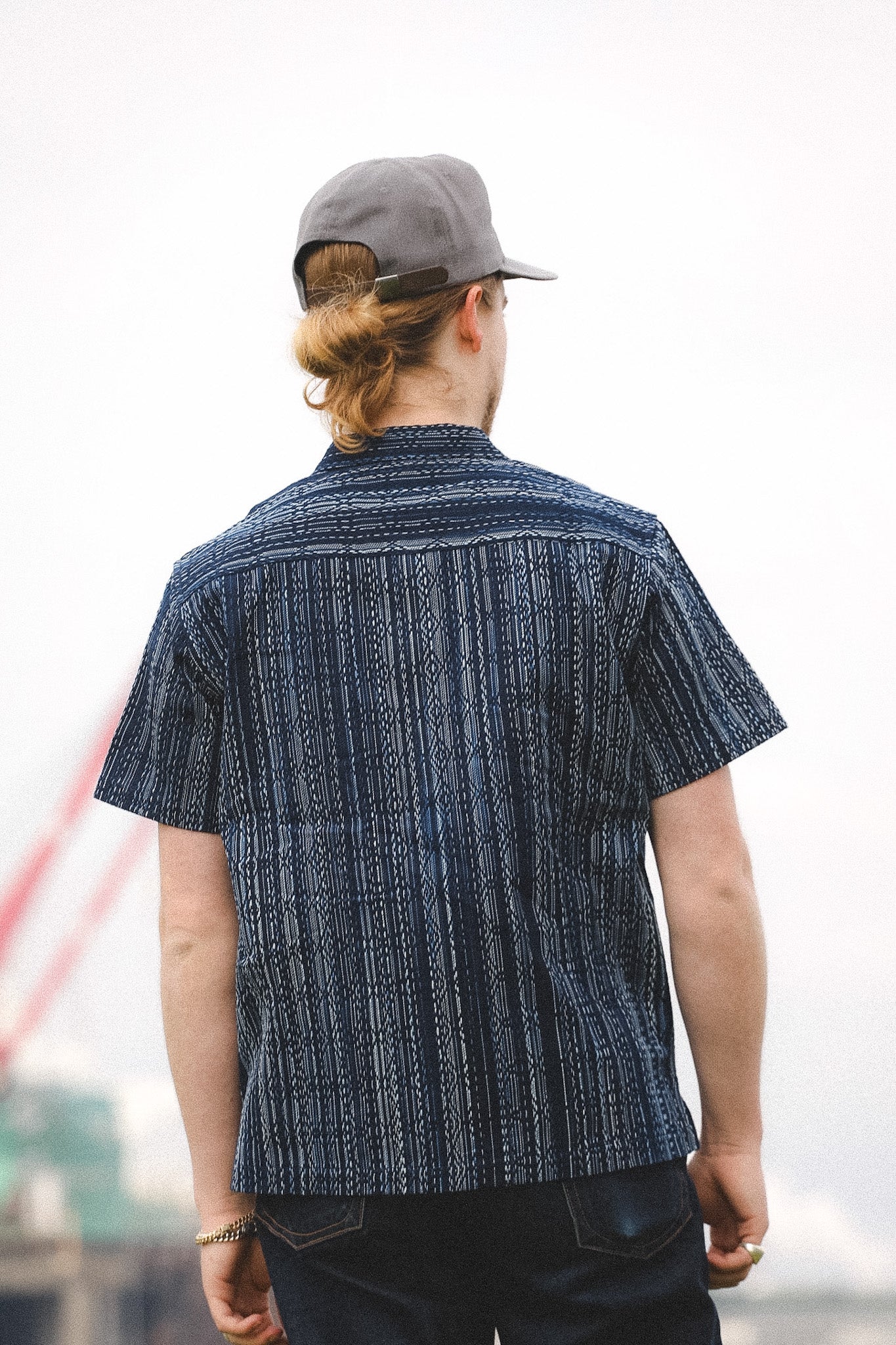 Person wearing a patterned shirt and cap with a blurred background
