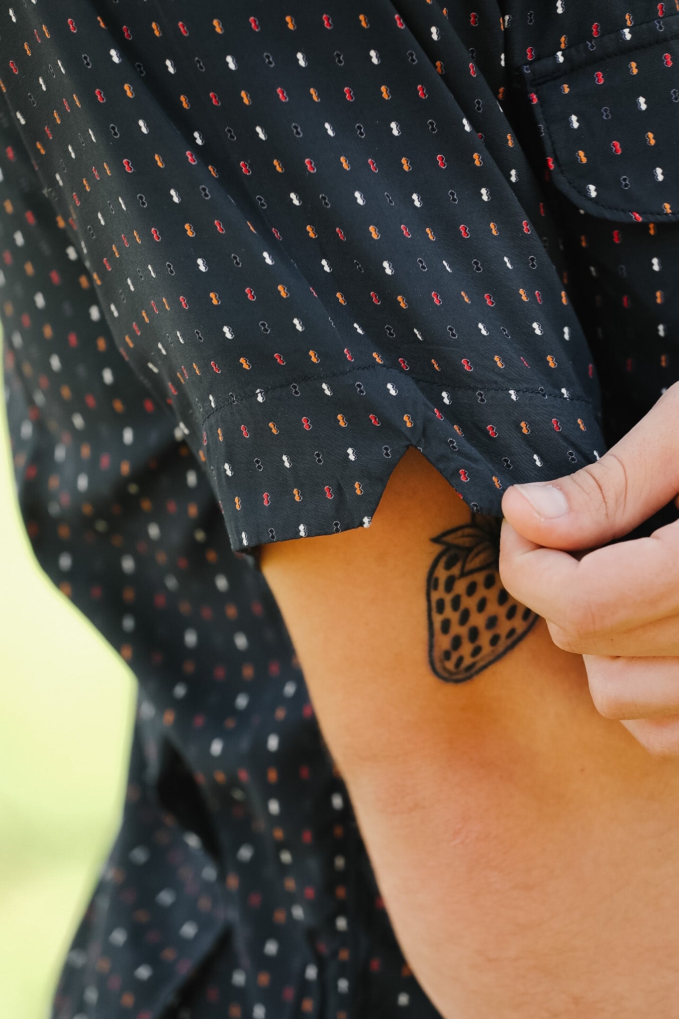 Close-up of a person wearing a dark patterned shirt with a blurred background