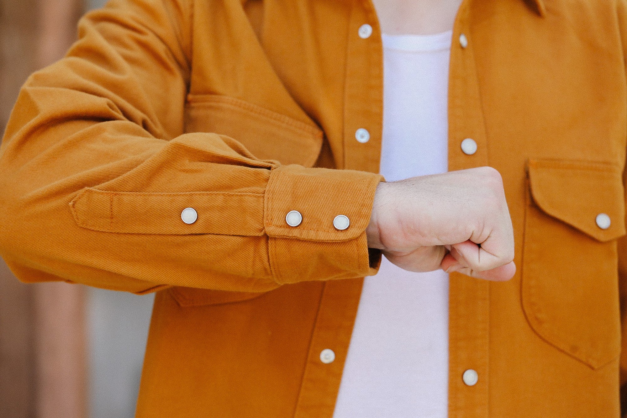 Close-up of a person wearing a rust orange button-up work shirt over a white shirt at Iron Shop Provisions