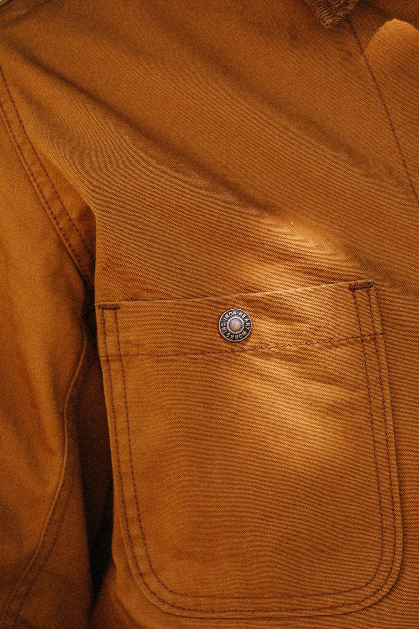Close-up of brown canvas work jacket pocket with iron rivet button from Iron Heart