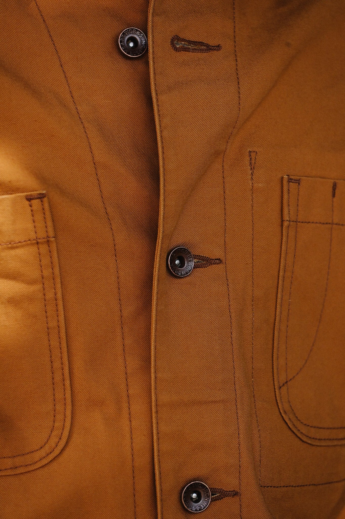 Close-up of brown iron-wear jacket with metal buttons and dual front pockets