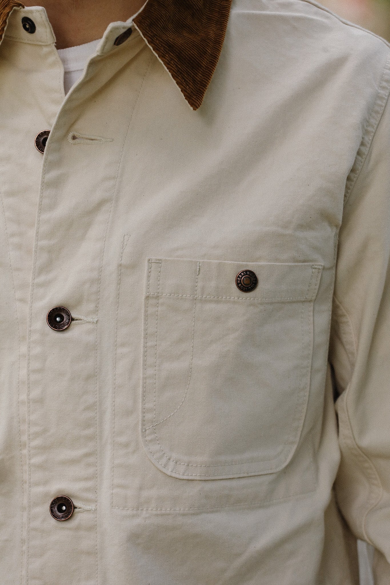 Close-up of beige work jacket with brown corduroy collar and metal buttons at Iron Shop Provisions