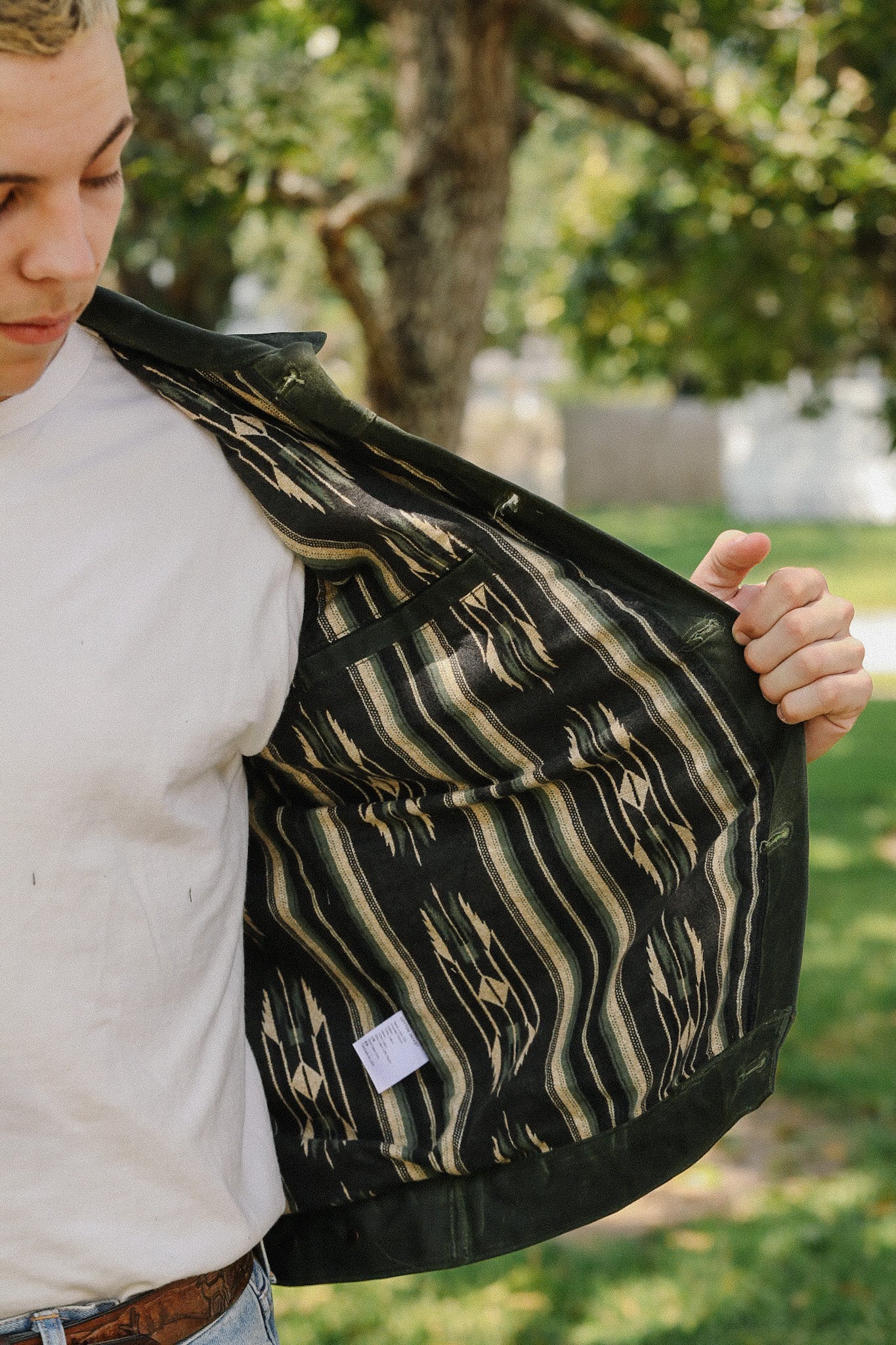 Close-up of man showing black jacket with patterned lining outdoors at Iron Shop Provisions