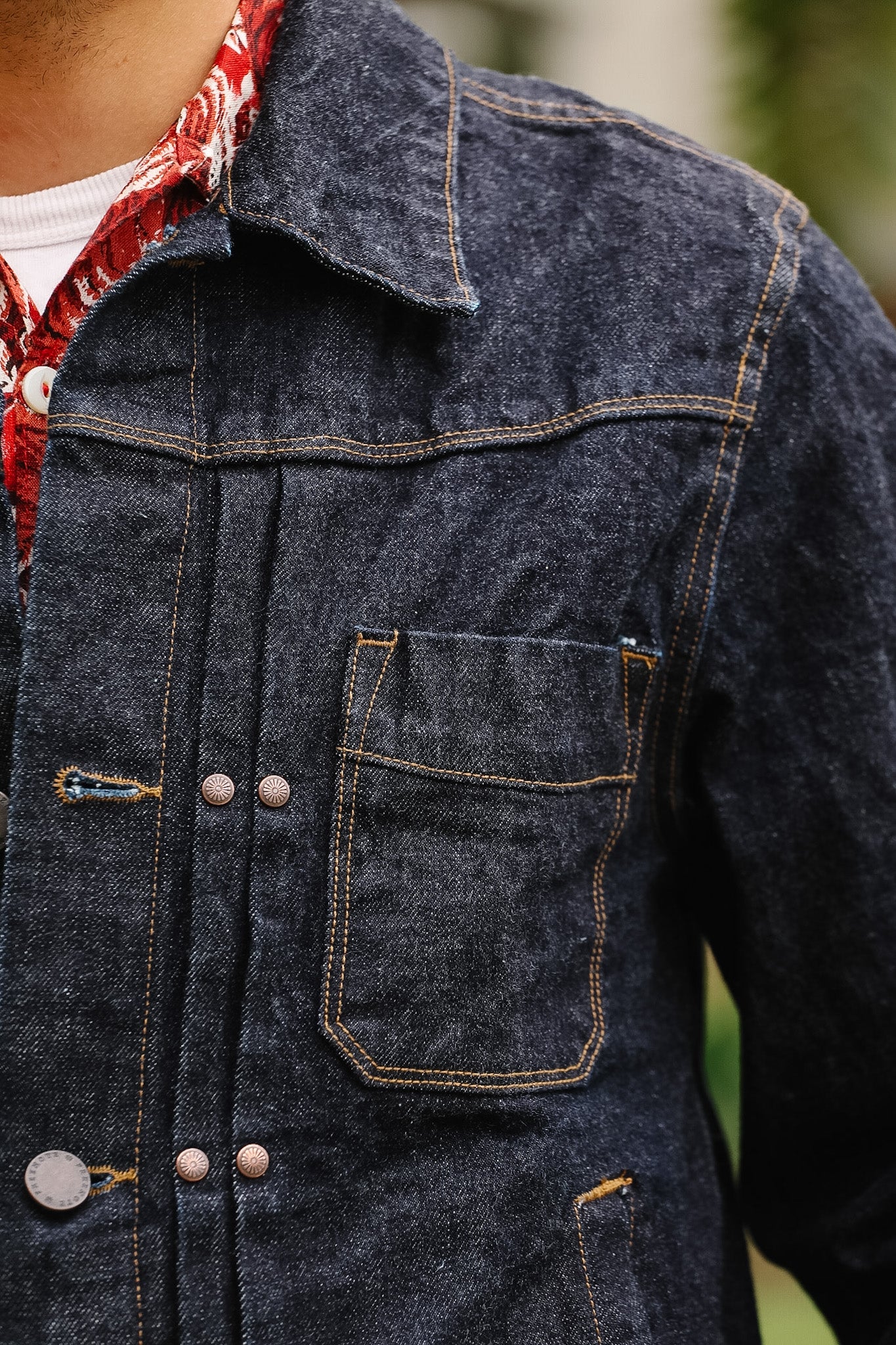 Close-up of a dark blue denim jacket with buttons and a pocket.